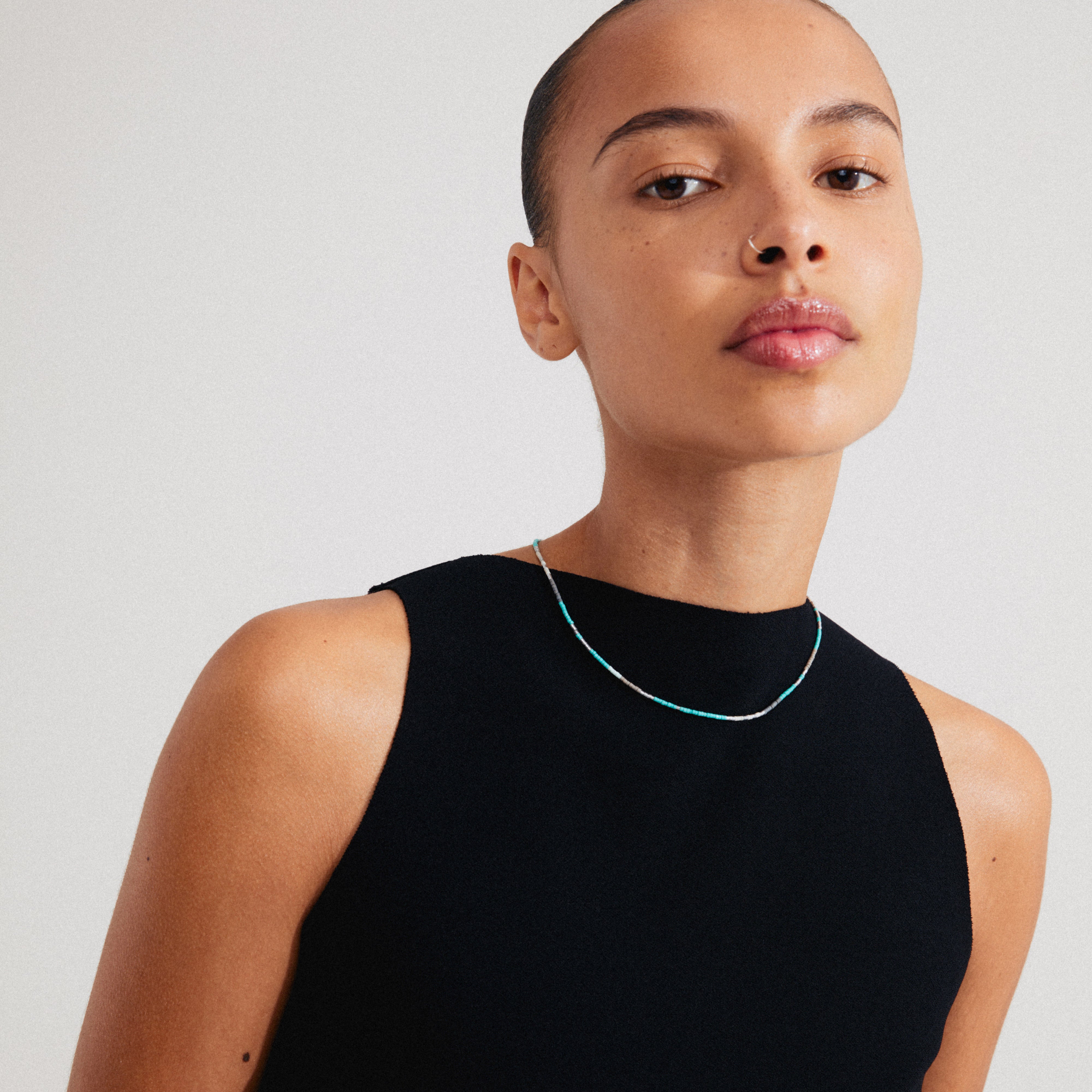 Woman wearing the ALISON necklace, featuring mint green and grey glass beads, worn close to the neck for a stylish, layered look.