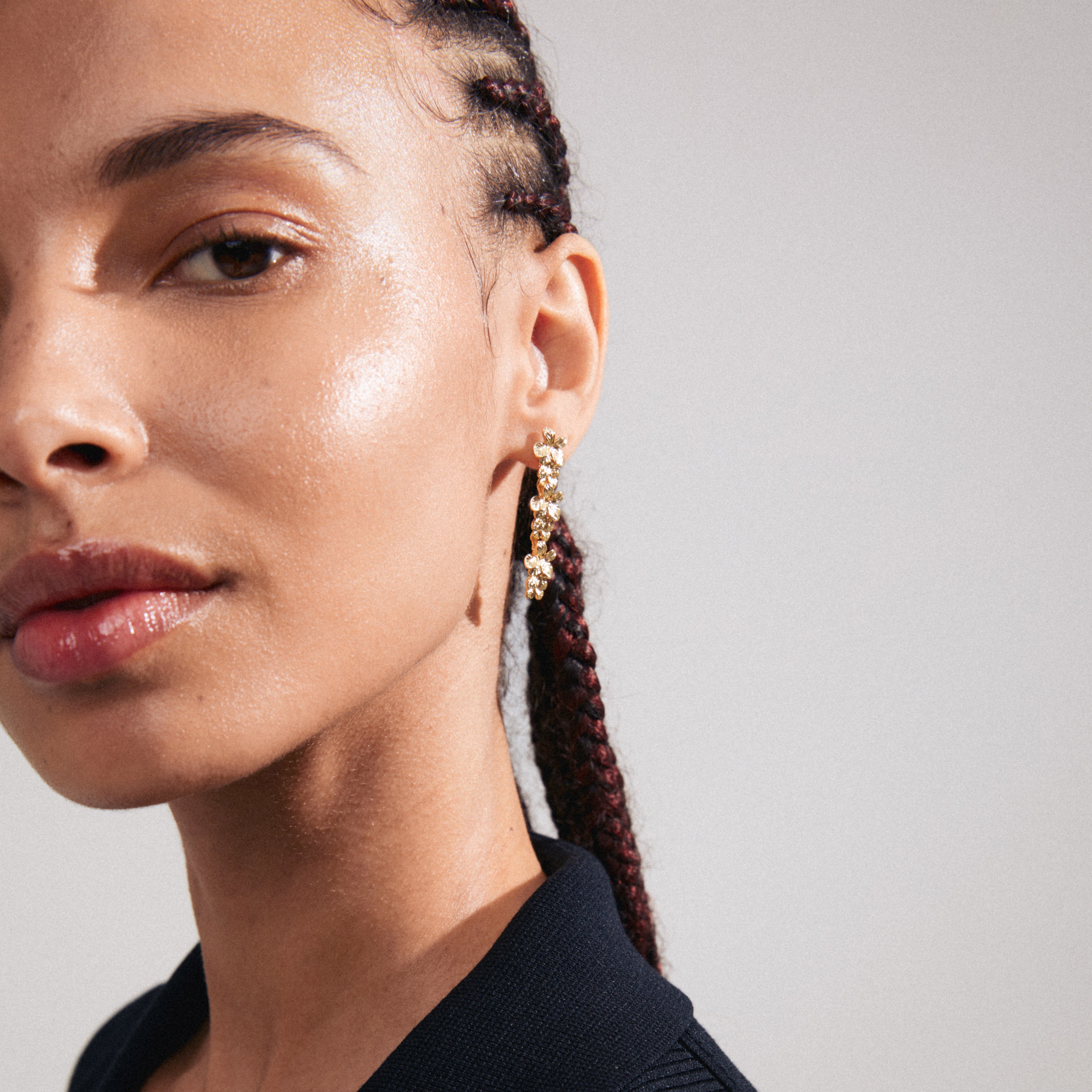 Close-up of a woman wearing gold-plated CHARMAINE earrings, featuring a floral and oriental design, embodying Pilgrim's boho-luxe style.
