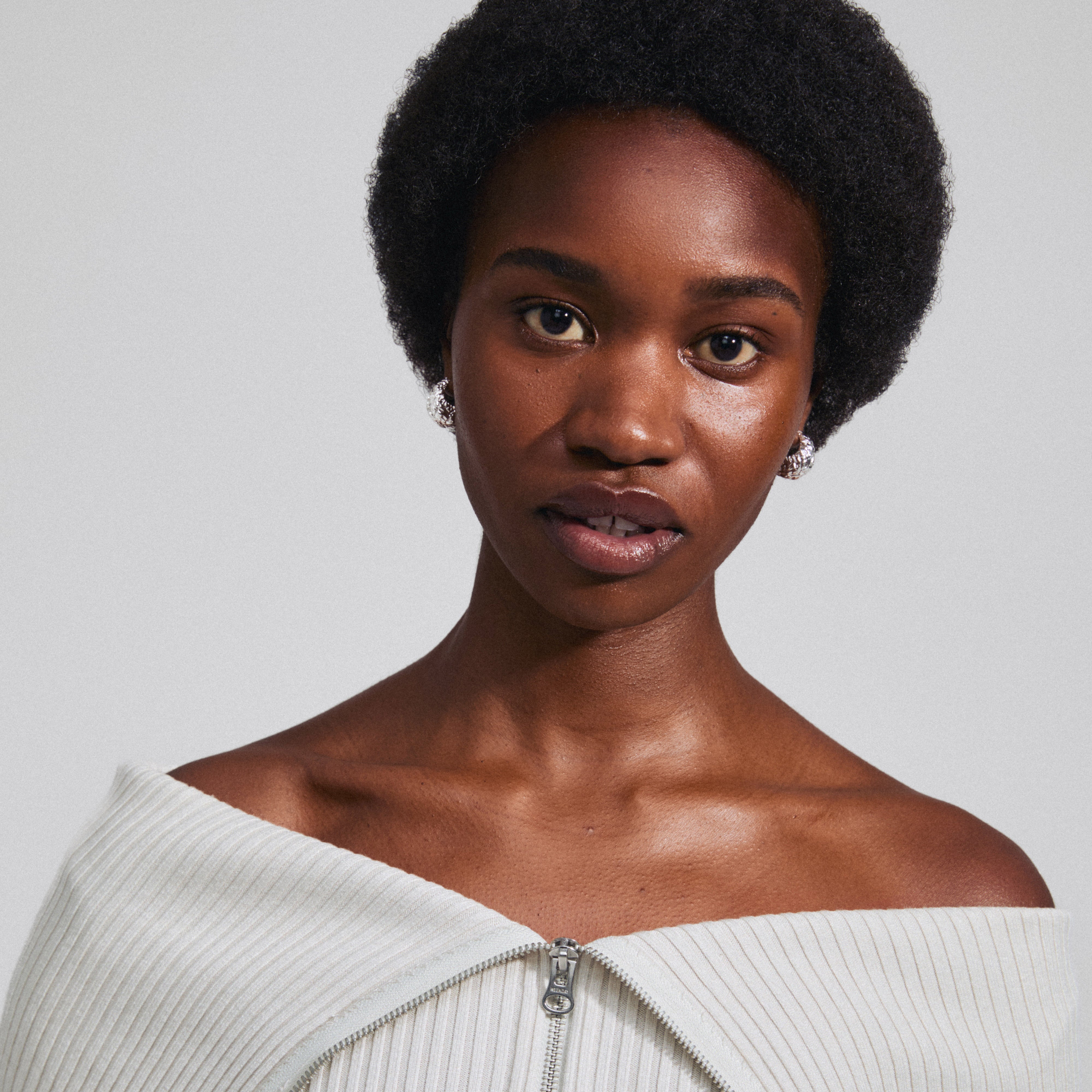 Woman wearing LINCOLN silver-plated earrings by Pilgrim, showcasing chunky, rustic hoops with shiny finish and easy click clasp.
