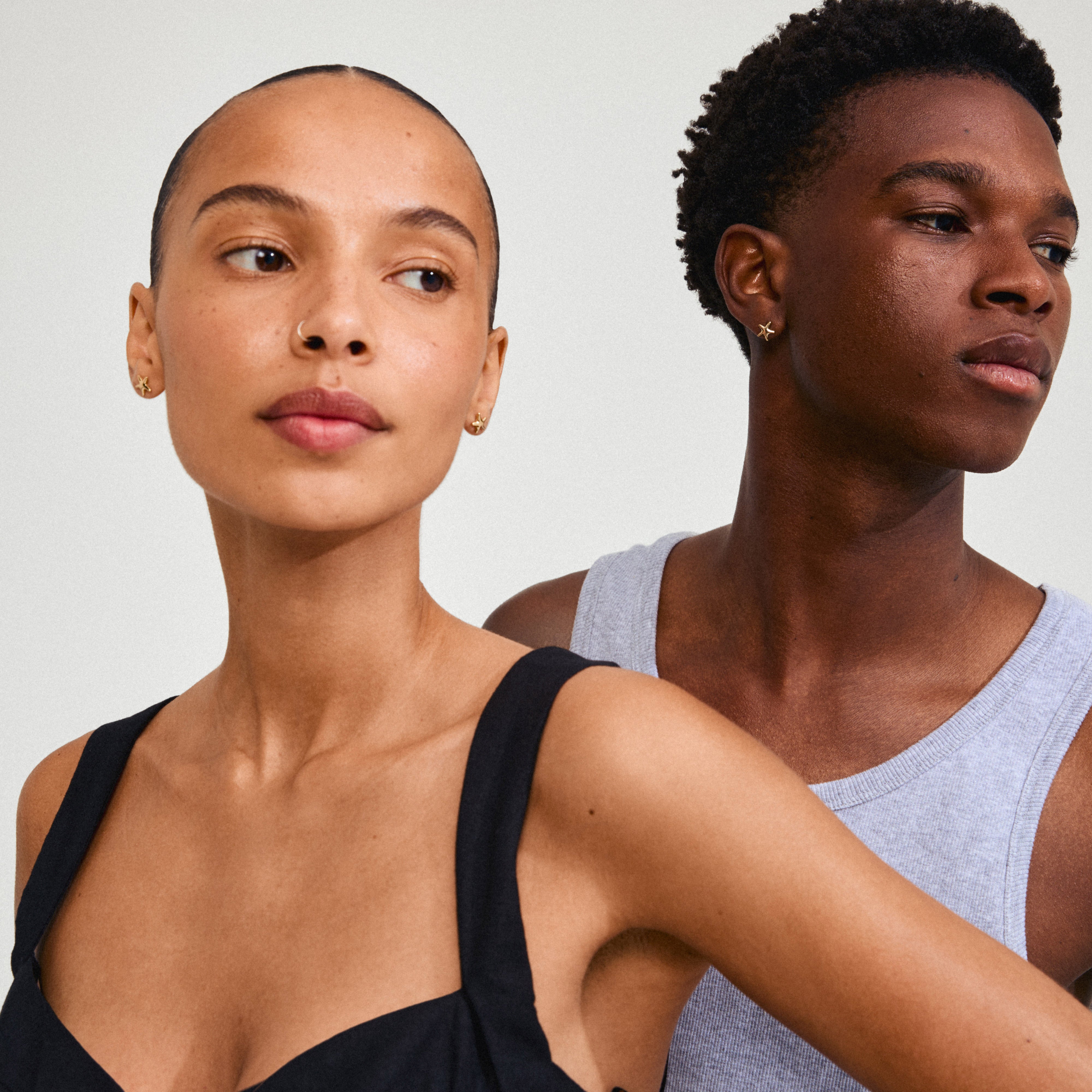 Man and woman wearing Pilgrim's gold-plated ANDRÉ earrings, featuring small starfish studs, embodying minimalistic summer vibes and crafted from recycled materials.