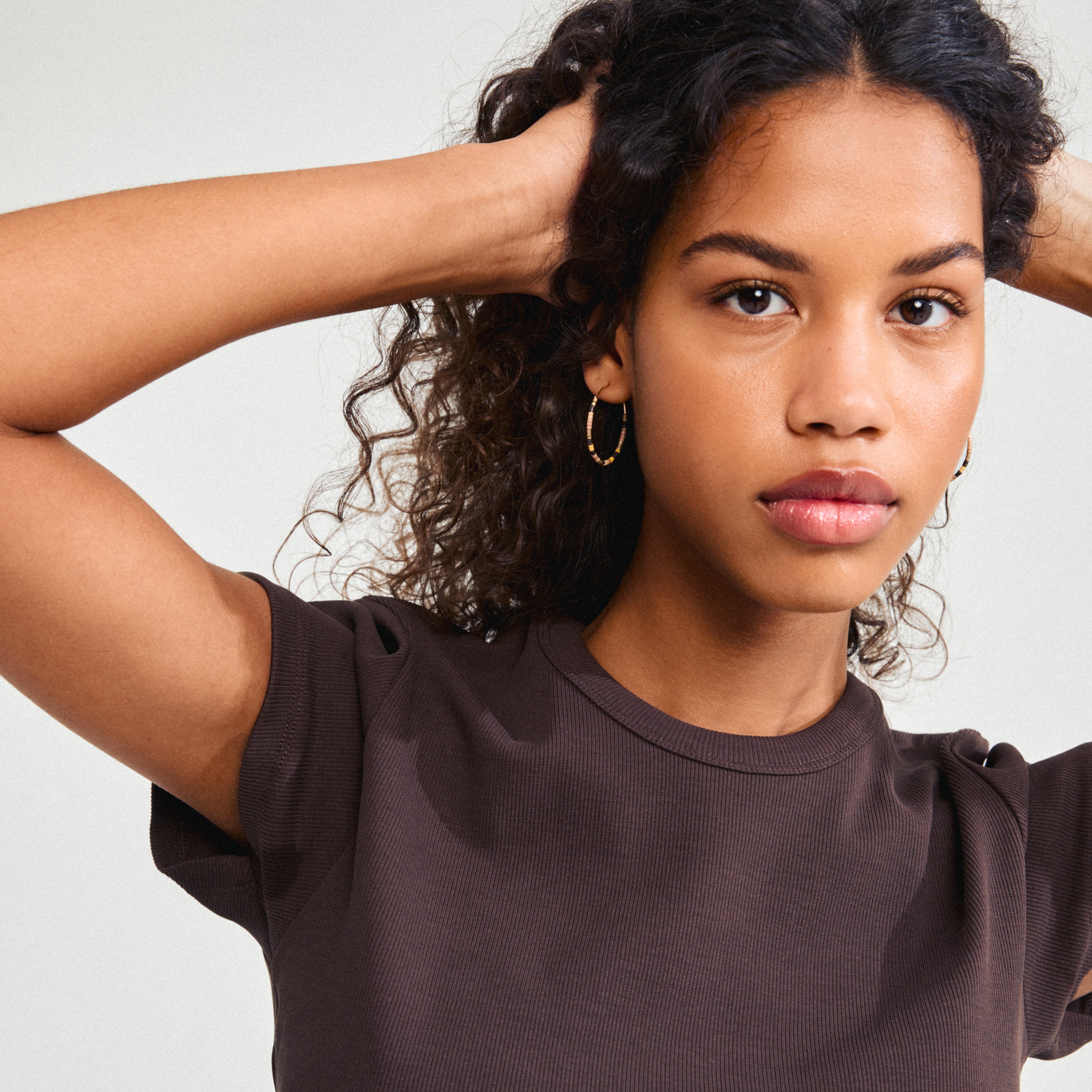 Close-up of a woman wearing APPOLLONIA gold-plated earrings, showcasing beaded hoops ideal for a relaxed summer style.