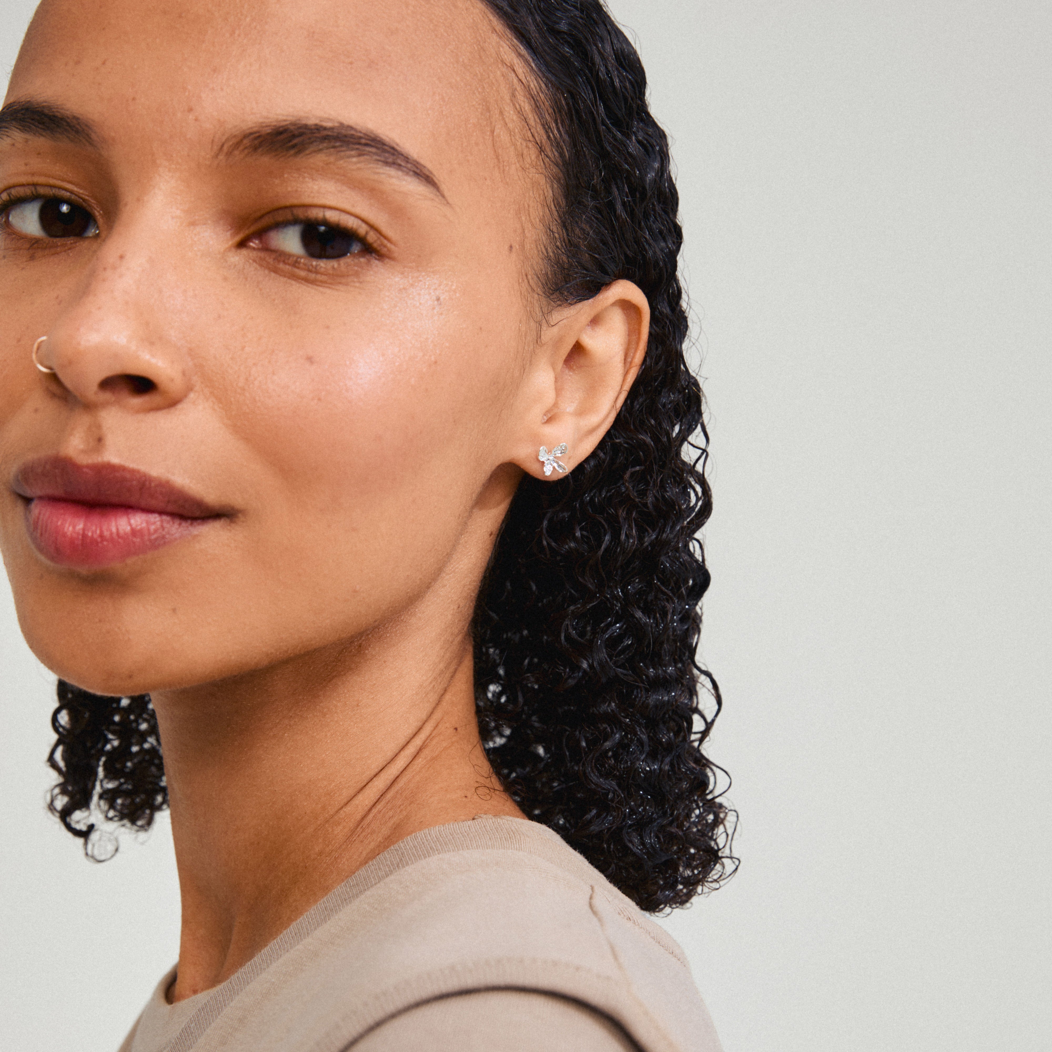 AGLAIA earrings silver-plated, featuring a delicate floral design, worn by a woman with curly hair and a nose ring, embody Pilgrim's artistic essence.