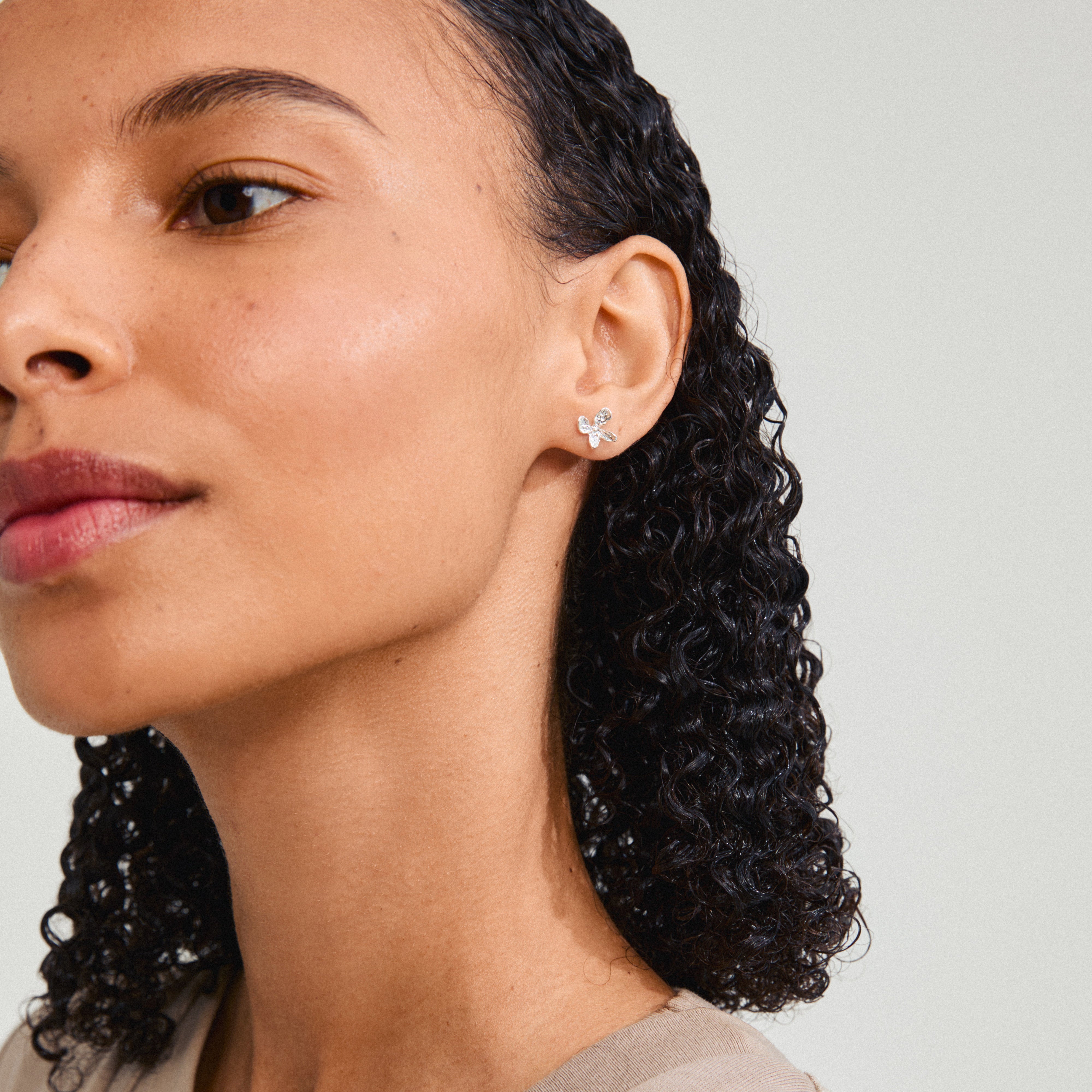 AGLAIA earrings silver-plated, featuring a delicate floral design, adorn a woman’s ear, highlighting Pilgrim's artistic essence and eco-friendly craftsmanship.
