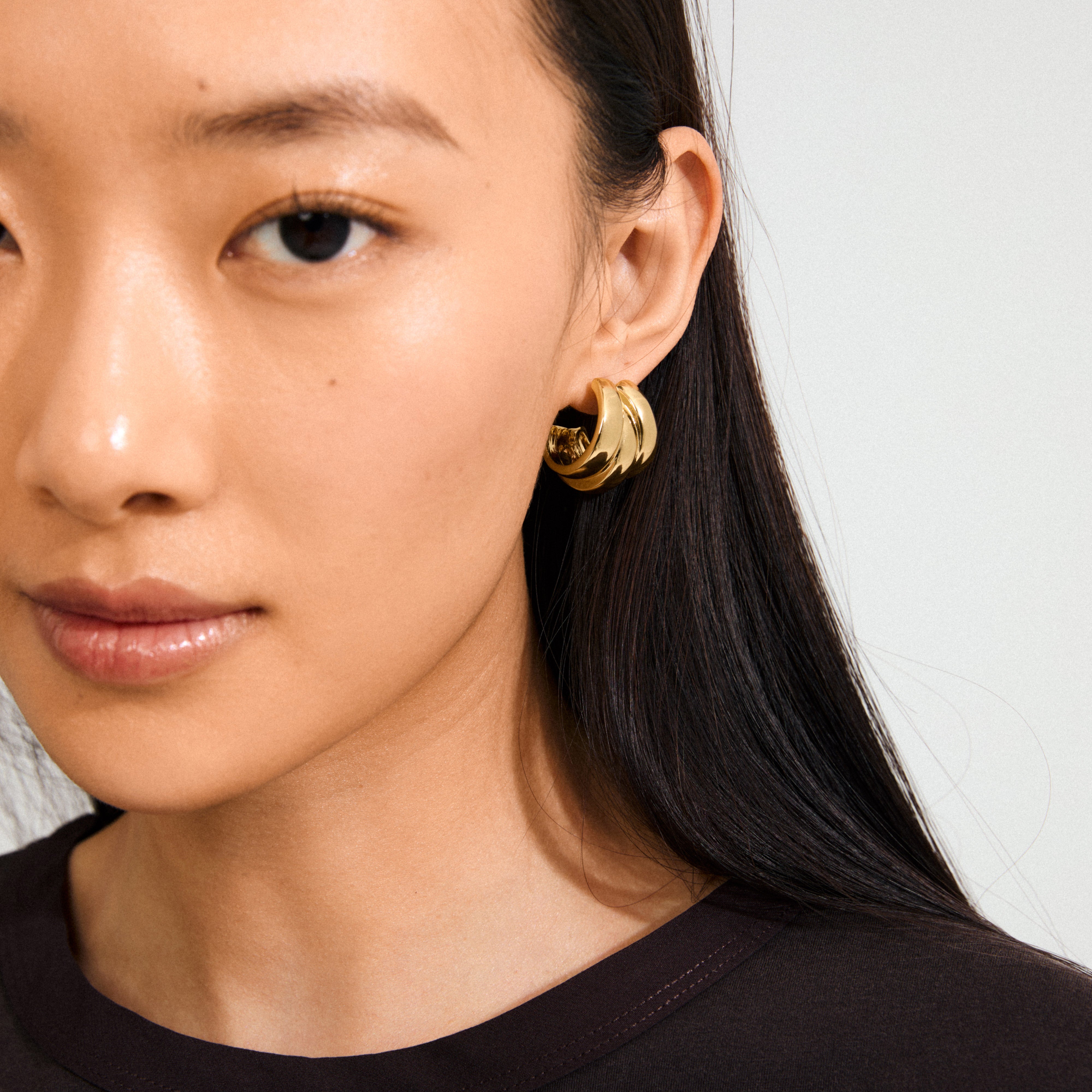 Close-up of a young woman wearing Pilgrim’s DAMIAN gold-plated earrings, featuring a chunky, multi-loop design, creating an impactful and trendy statement.
