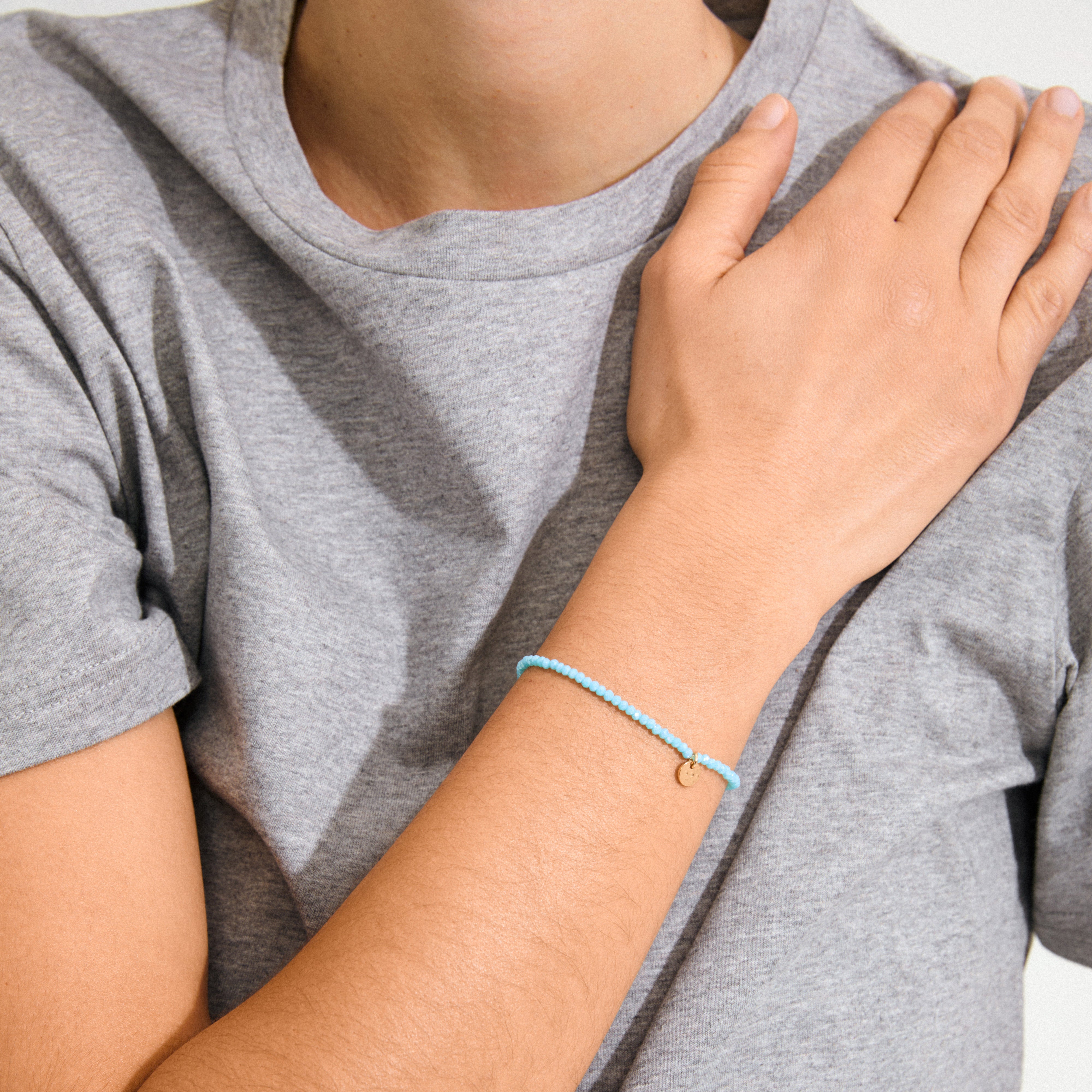 Person wearing the INDIE bracelet in sky blue and gold-plated design, featuring faceted glass beads, showcasing its stylish and versatile appeal for any occasion.