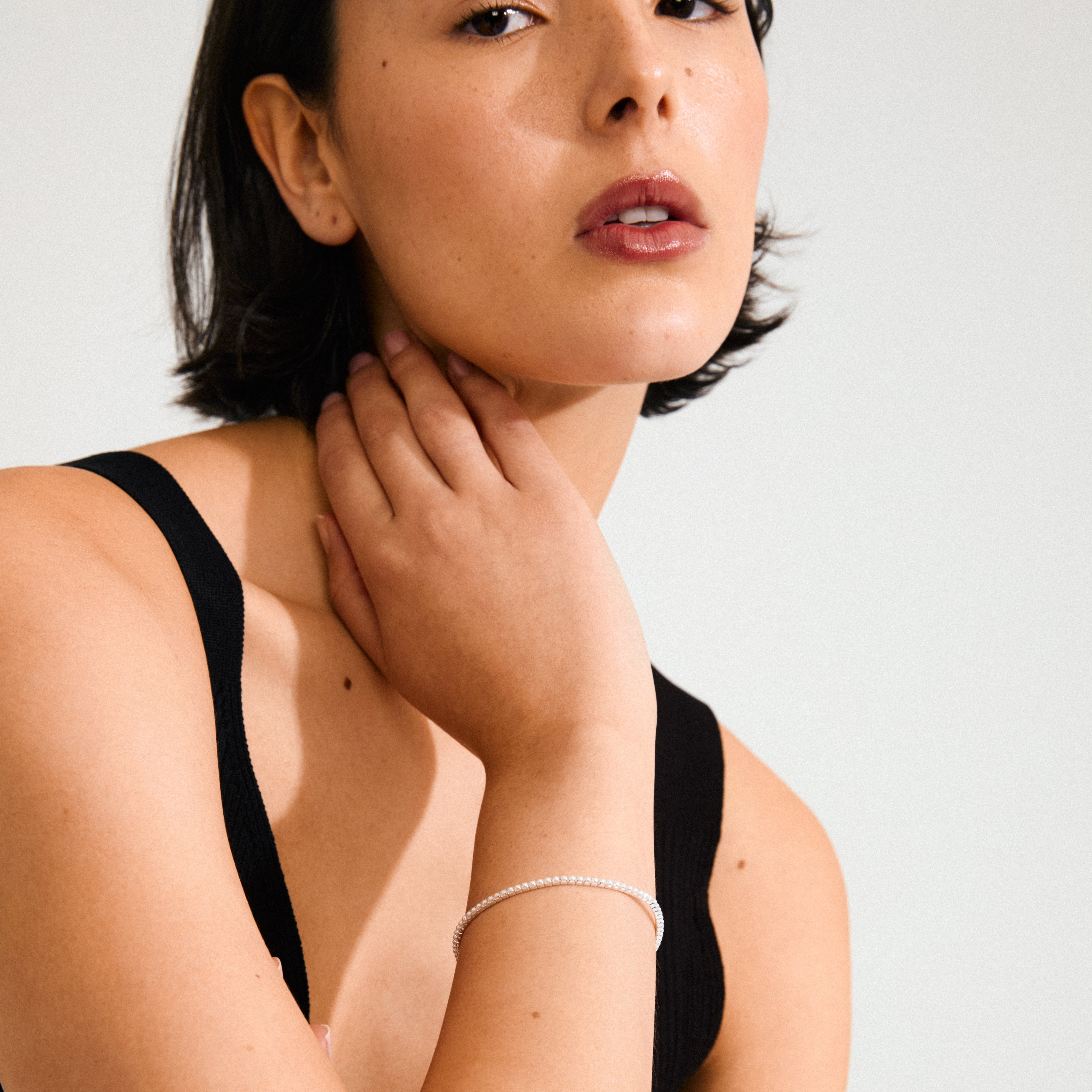 Woman wearing ARASH pearl bracelet, silver-plated with mother-of-pearl beads, showcasing its sleek design and comfortable fit on her wrist.