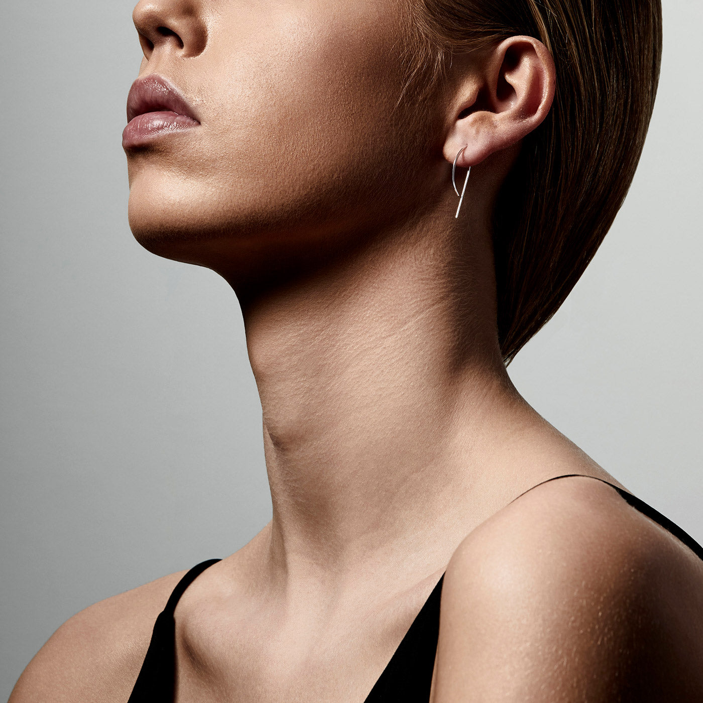A woman with a short haircut wears PEONY earrings, showcasing their simple, elegant silver-plated pull-through wire design.