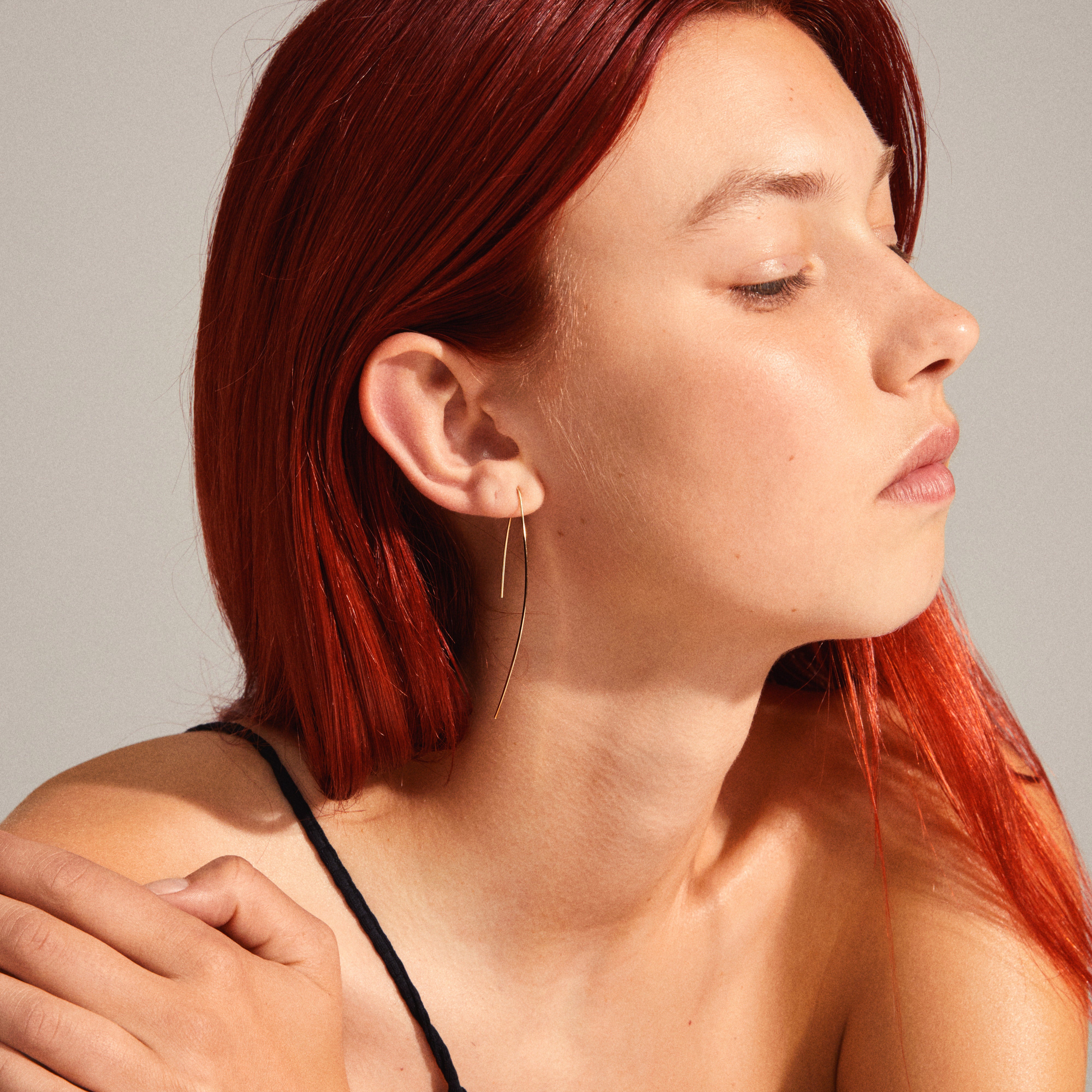 GRACE earrings gold-plated on a red-haired woman, showcasing their sculptural, angular design and open, contemporary expression.