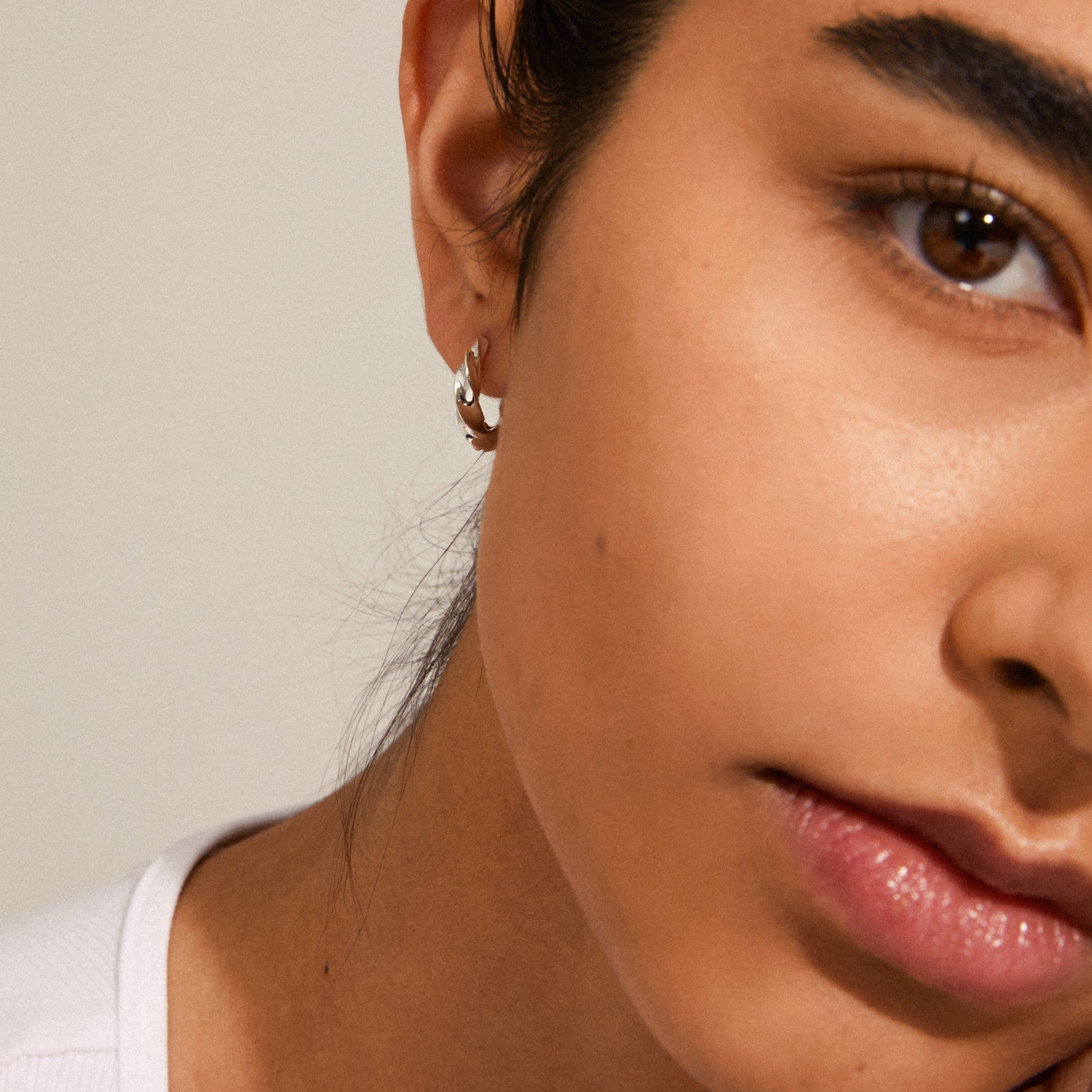 Close-up of a woman wearing Pilgrim's TAFFY medium-sized silver-plated swirl hoop earrings, showcasing their edgy and feminine design.