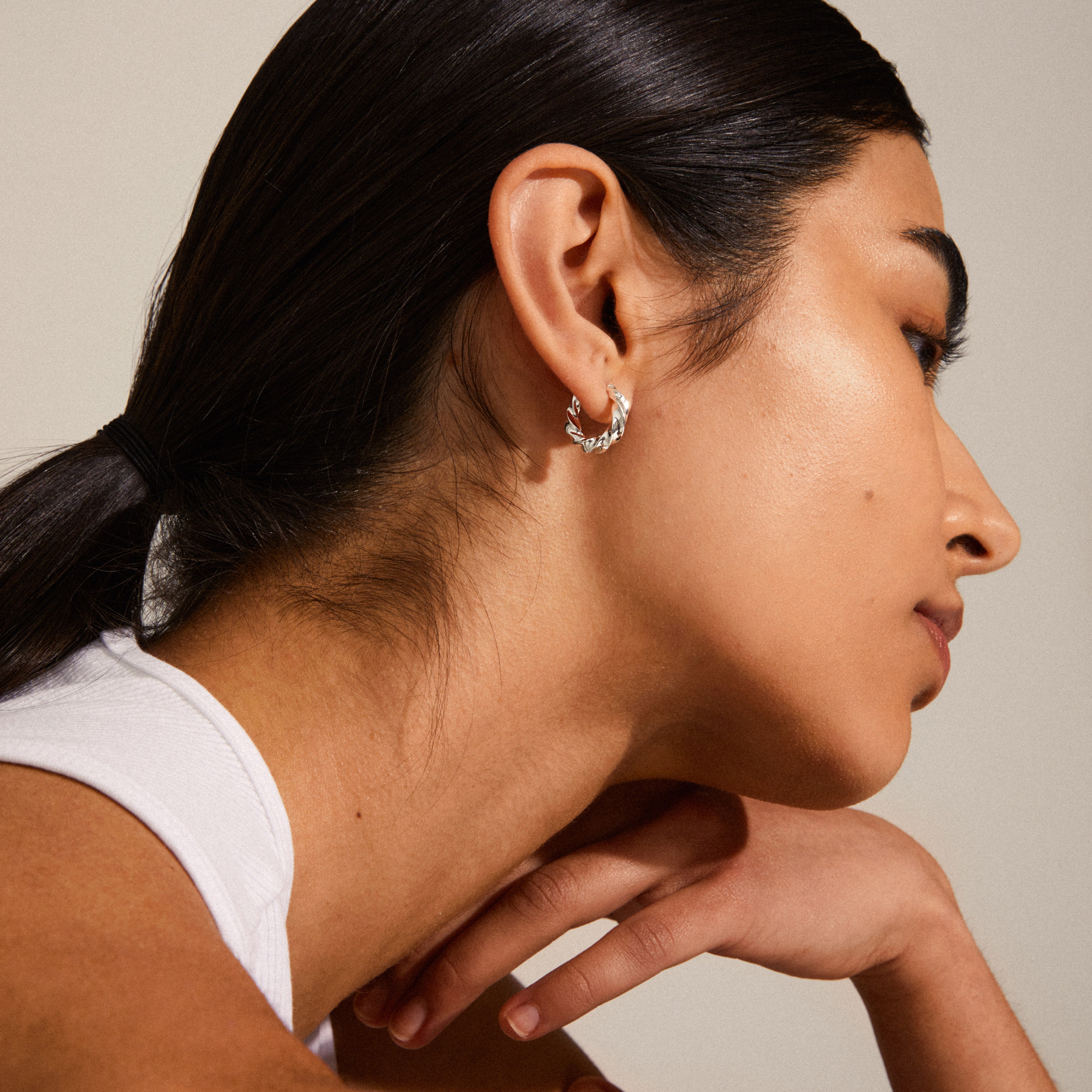 TAFFY medium size swirl hoop earrings, silver-plated, adorn a woman's ear with an elegant, vintage-inspired design, highlighting Pilgrim's Scandinavian craftsmanship.