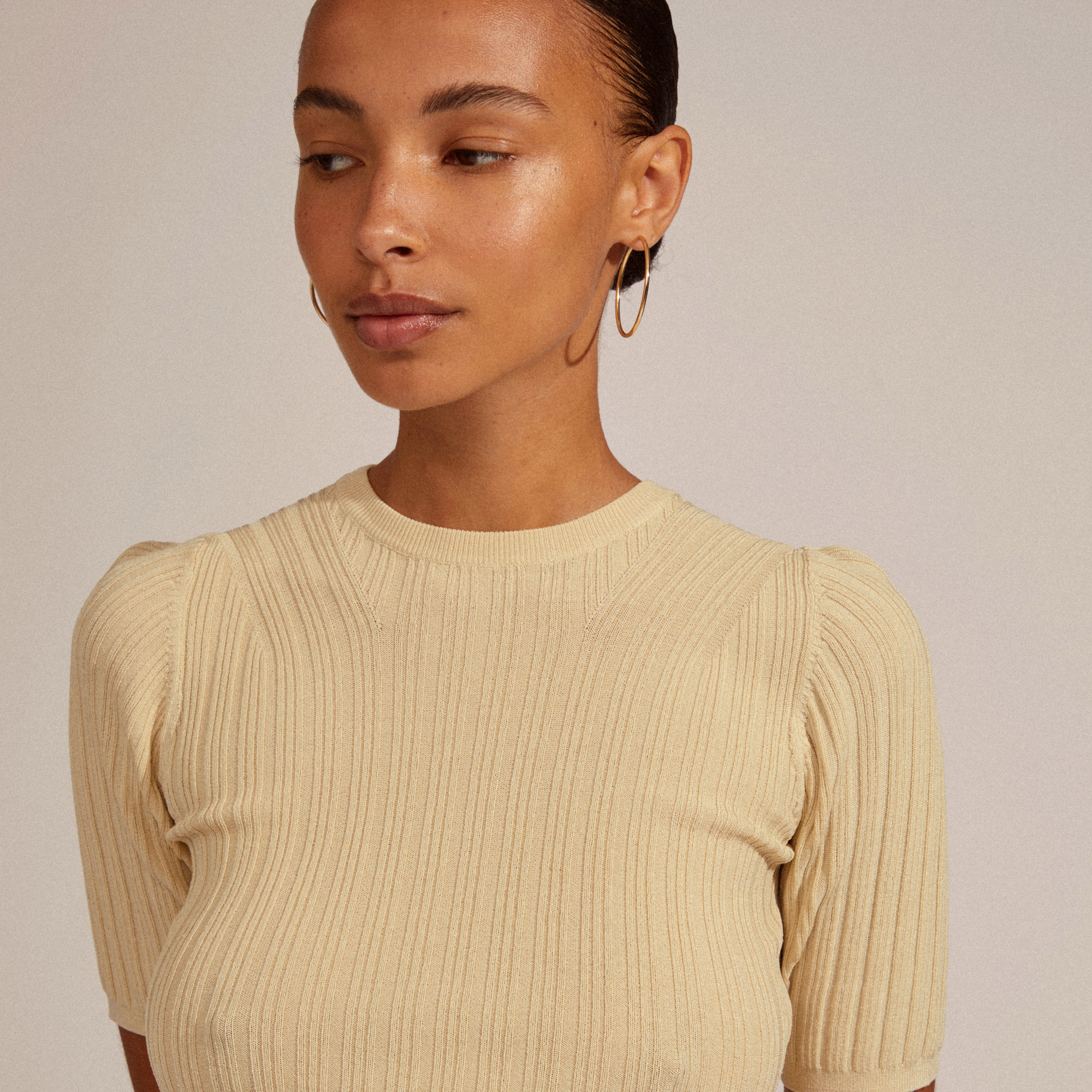 Woman wearing APRIL medium-size gold-plated hoop earrings, showcasing their versatility and timeless style. Perfect for trendy ear curation, aligning with Pilgrim's inclusive and fashionable ethos.