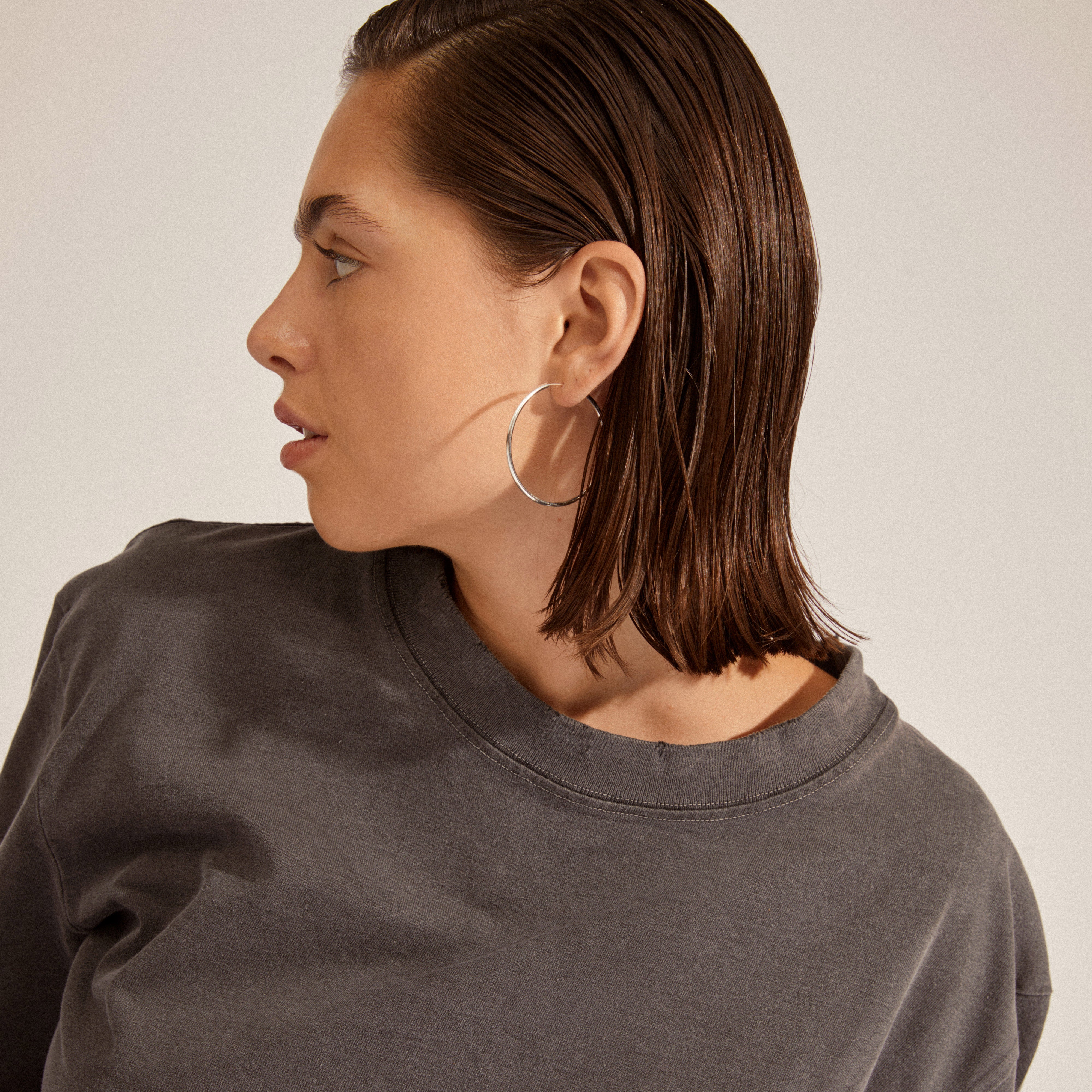 Silver-plated medium hoop earrings showcased on a woman, capturing their elegant simplicity and versatile style. Ideal for personal expression and mix-and-match accessorizing.