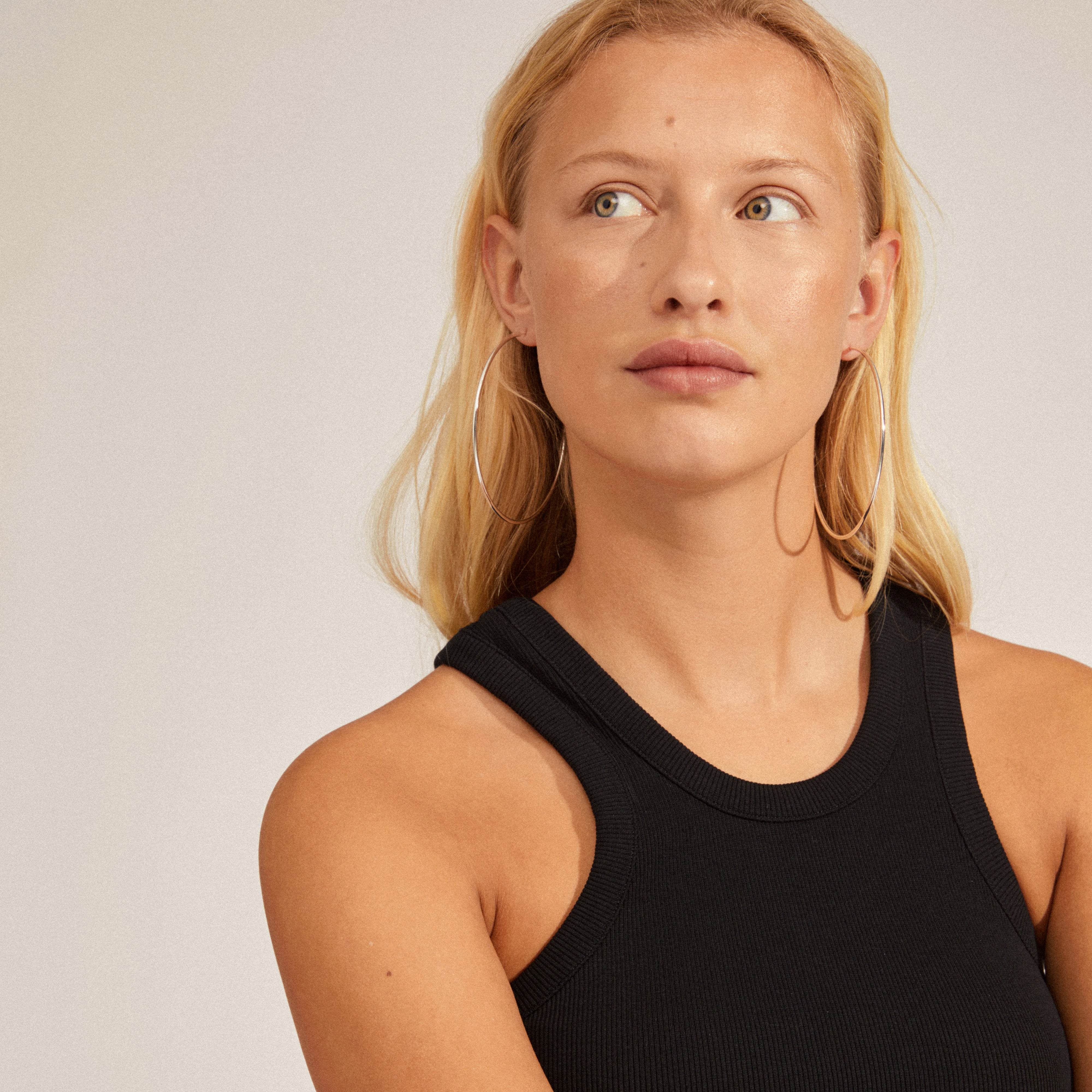 Silver-plated APRIL maxi hoop earrings from Pilgrim, elegantly styled on a woman's neck, showcasing their large, airy design perfect for a sassy, trendy look.