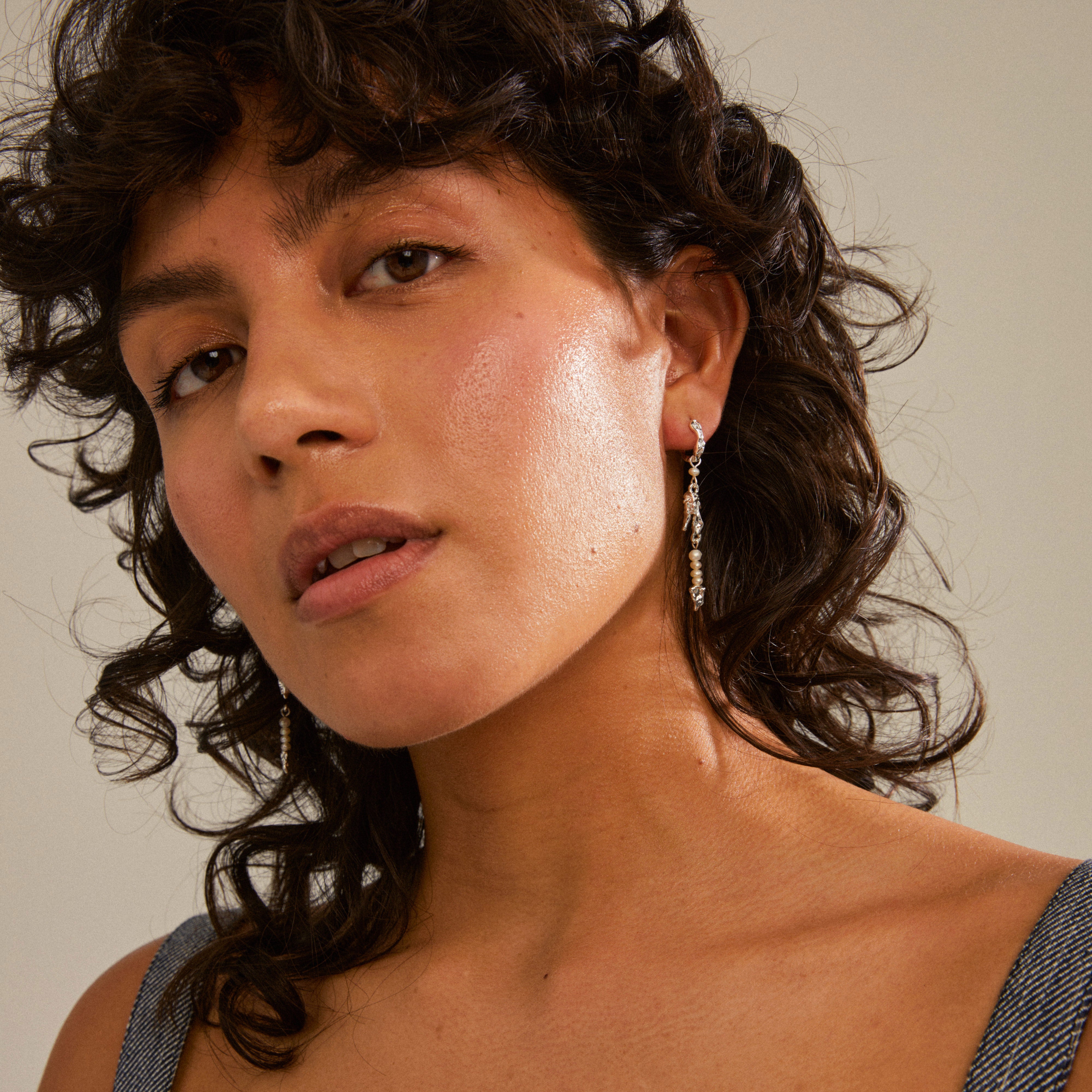 NIYA freshwater pearl earrings silver-plated on a woman with curly hair, highlighting the organic shapes and playful elegance of Pilgrim's handcrafted design.