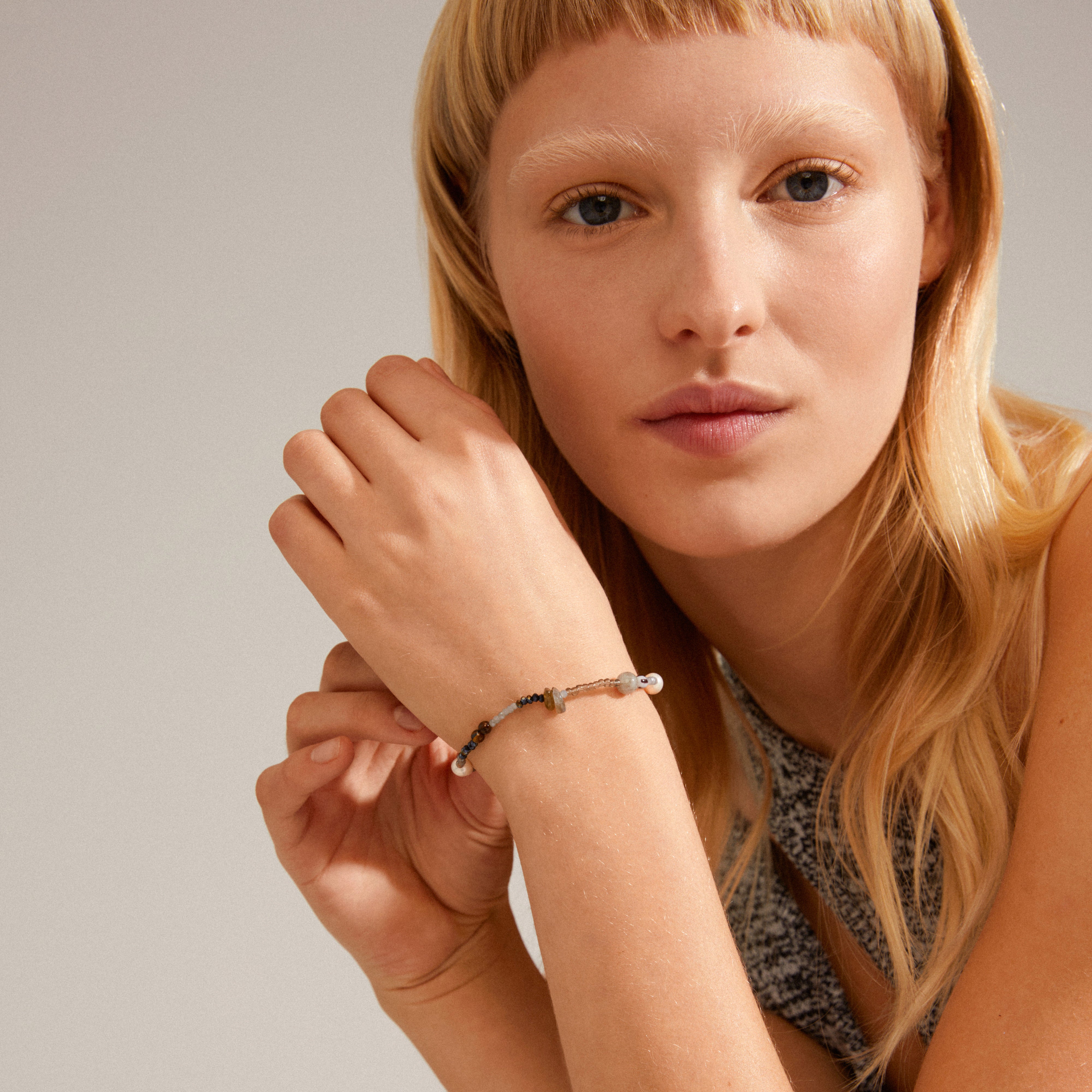 INDIANA bracelet grey showcased on a woman's wrist, featuring freshwater pearls, tiger's eye stones, and faceted glass beads, offering an effortless, organic look.
