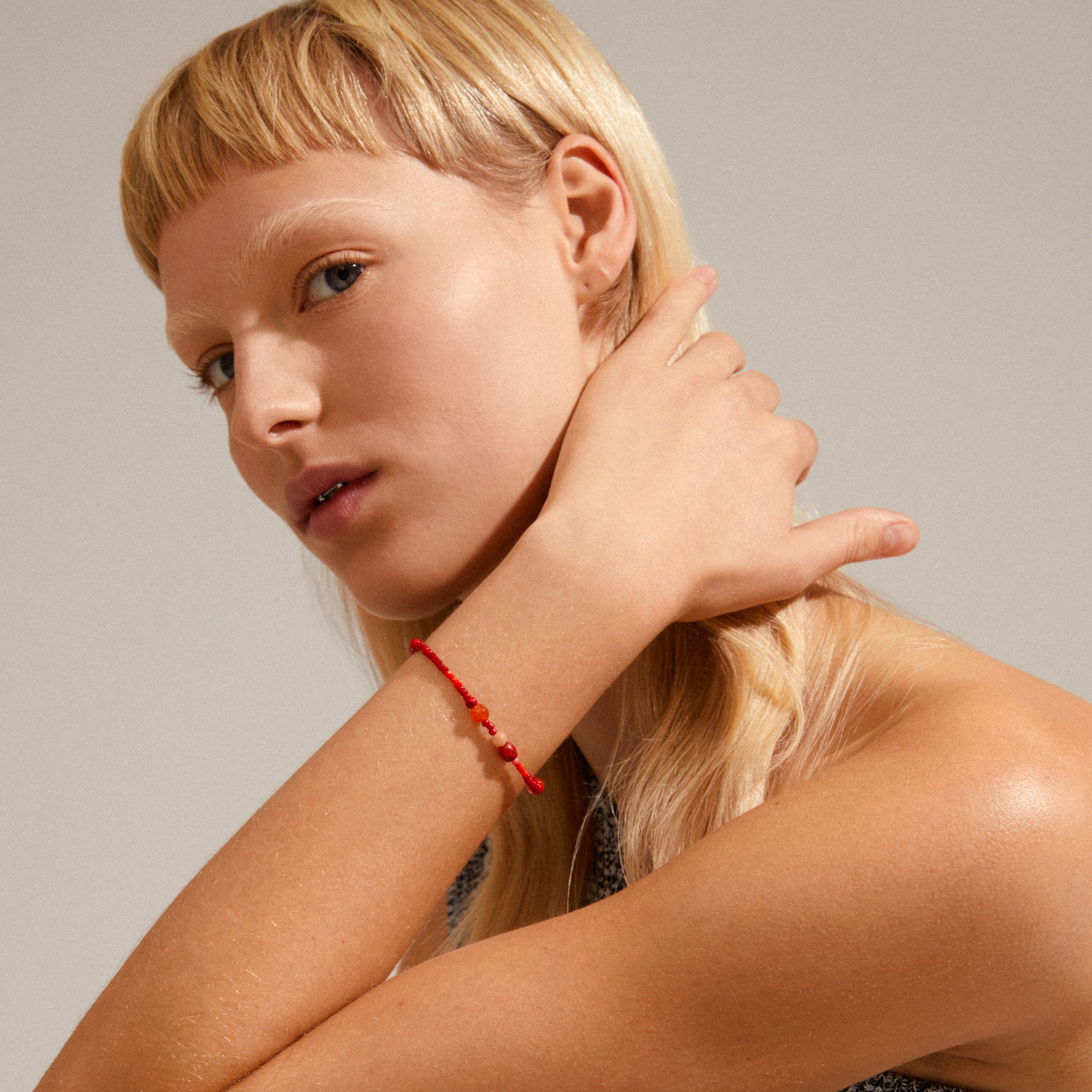 INDIANA bracelet red featuring genuine freshwater pearls, red agate, and faceted glass beads, displayed on a woman's wrist, showcasing its organic and stylish design.