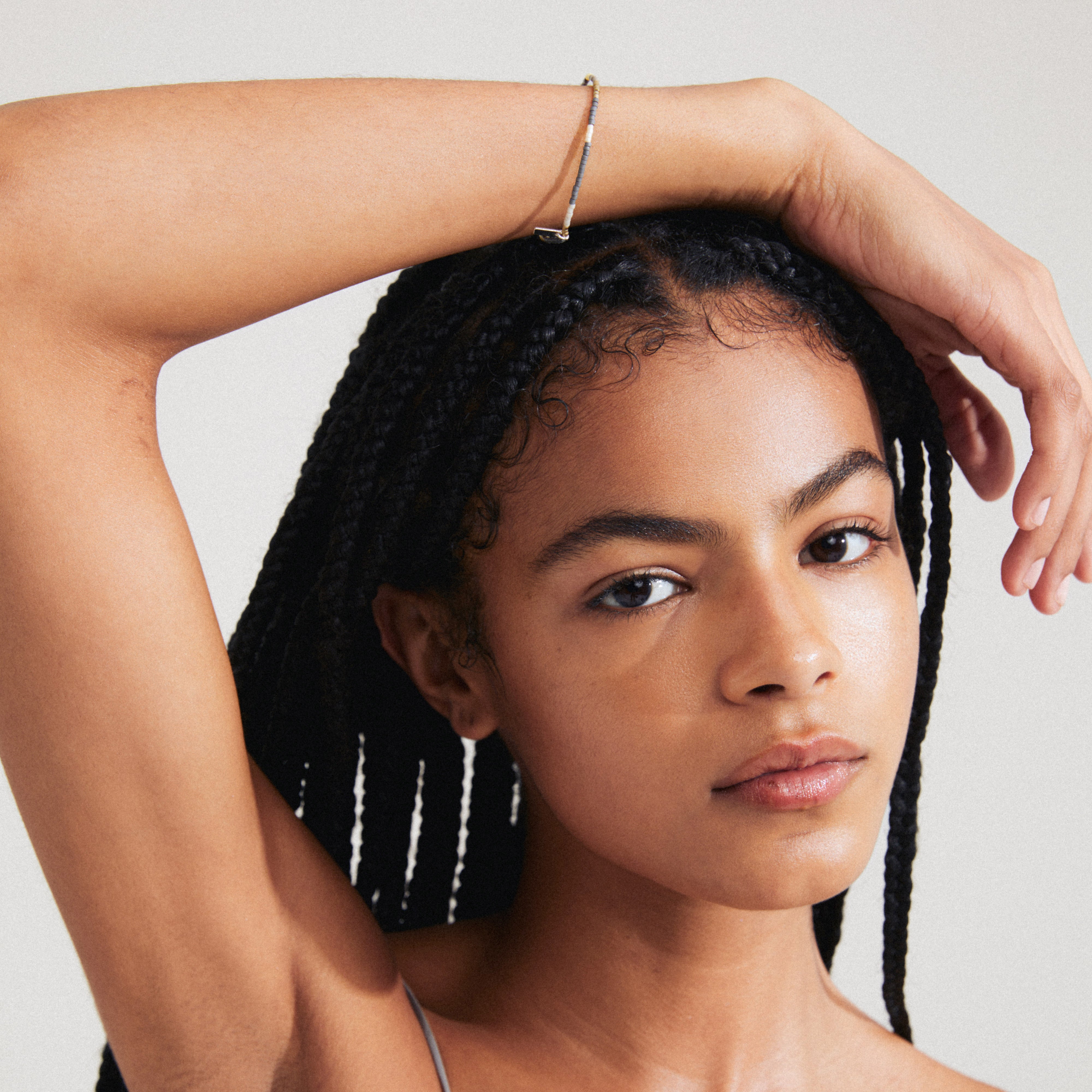 Woman wearing Pilgrim's ALISON bracelet in grey, showcasing glass beads on a lycra band, styled with boho-inspired fashion.