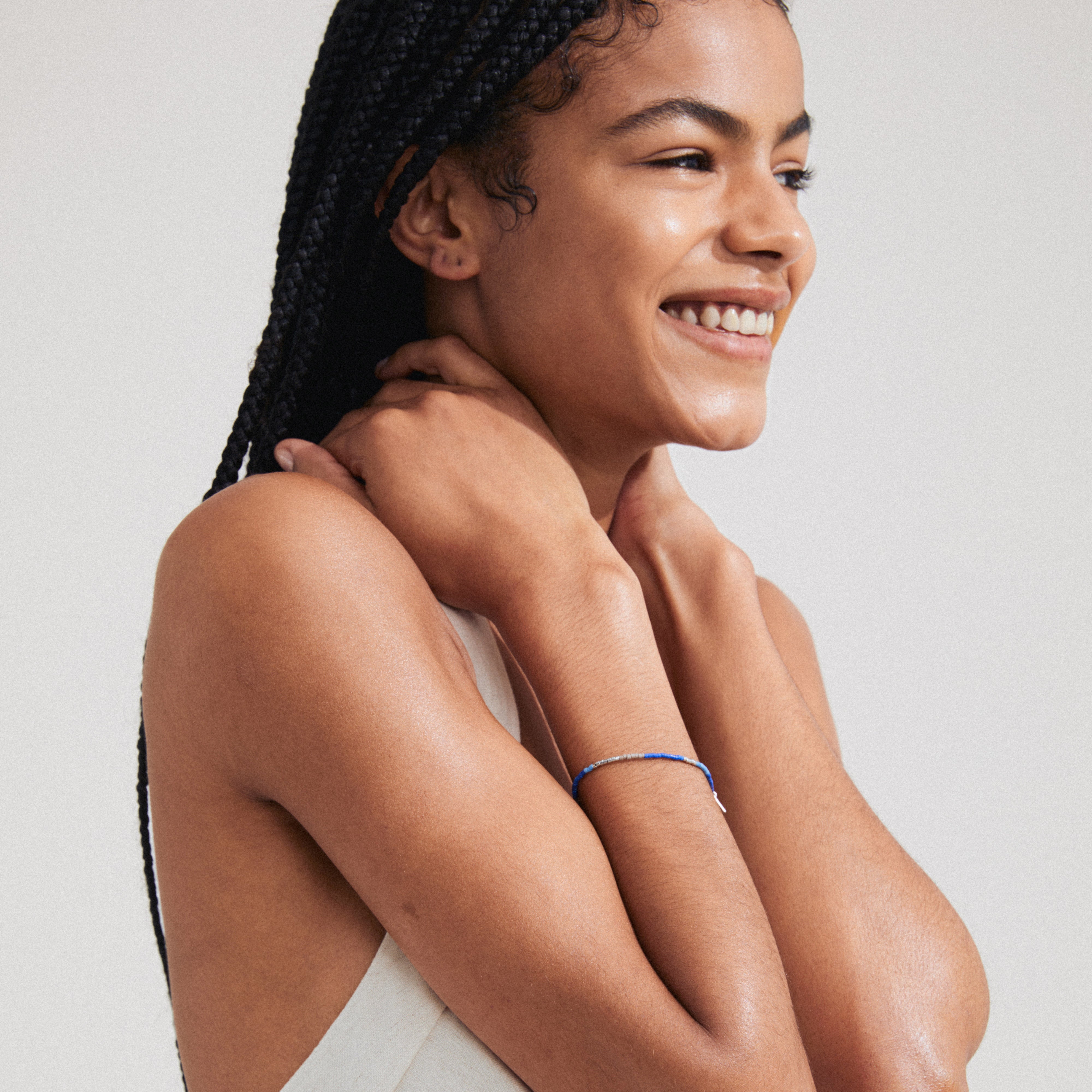 A woman smiles, showcasing the ALISON bracelet in blue and silver-plated beads, embodying a boho-inspired, laid-back style.
