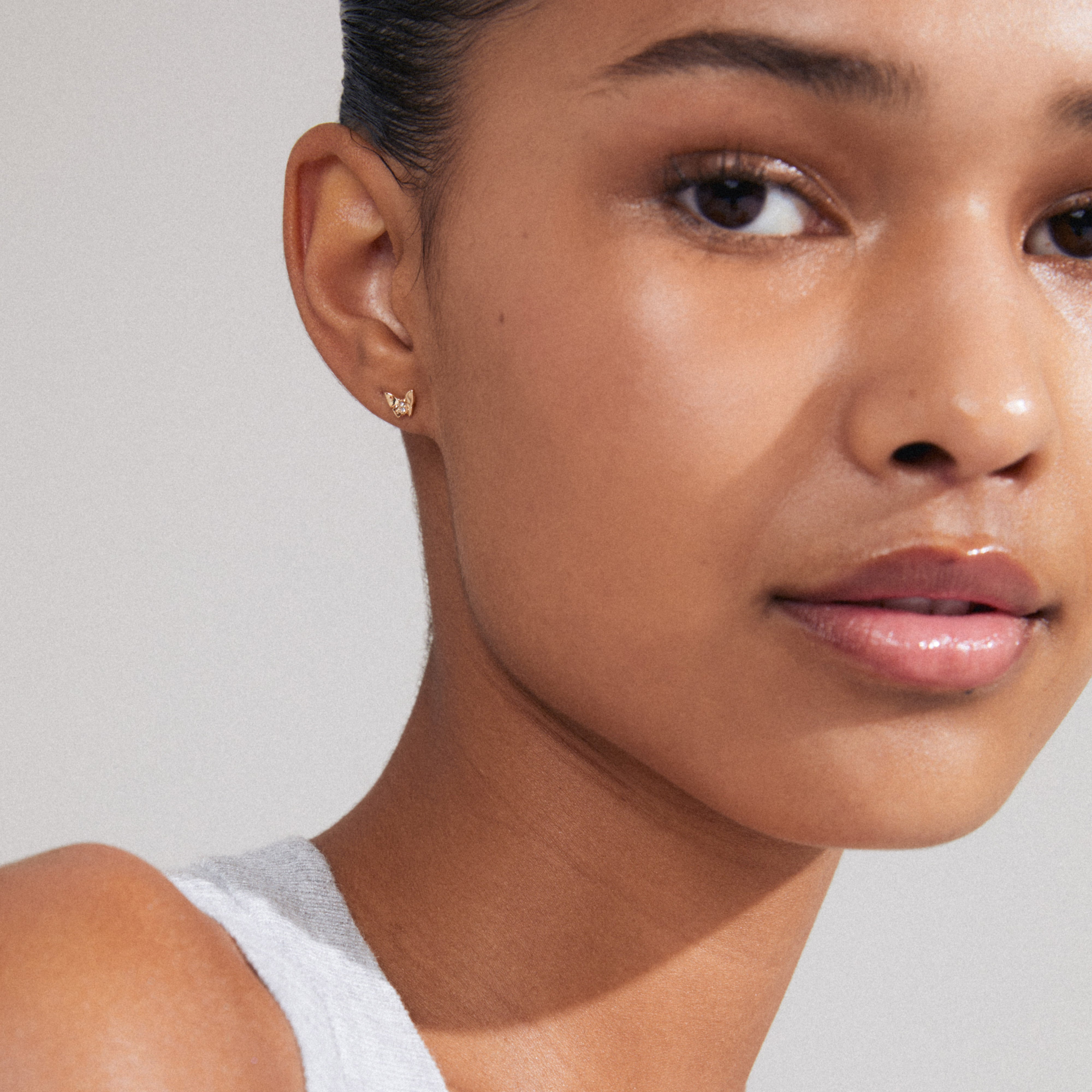 OLYMPIA gold-plated single earring on a woman’s ear, featuring a delicate butterfly design with Preciosa crystals, embodying change and beauty.