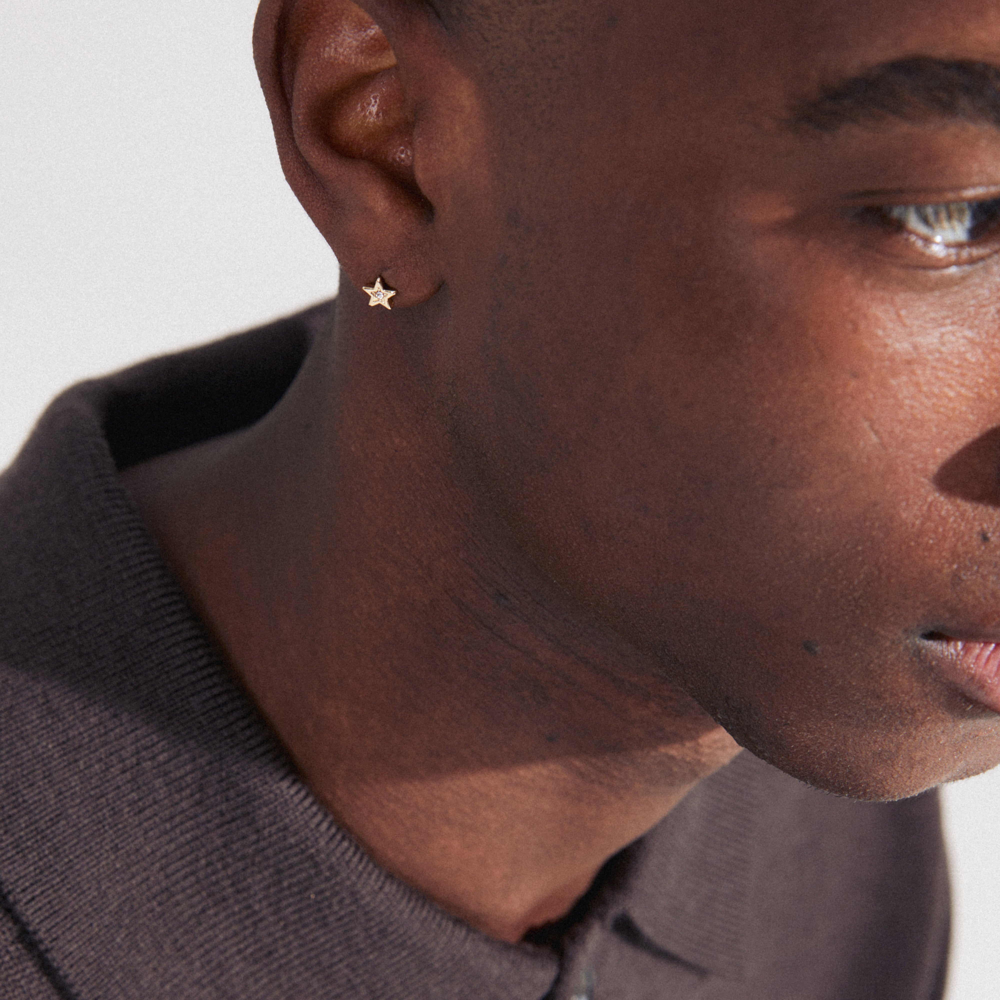 NYX single earring gold-plated, worn by a man, featuring a star design with a Preciosa crystal, ideal for trendy, asymmetrical styling.