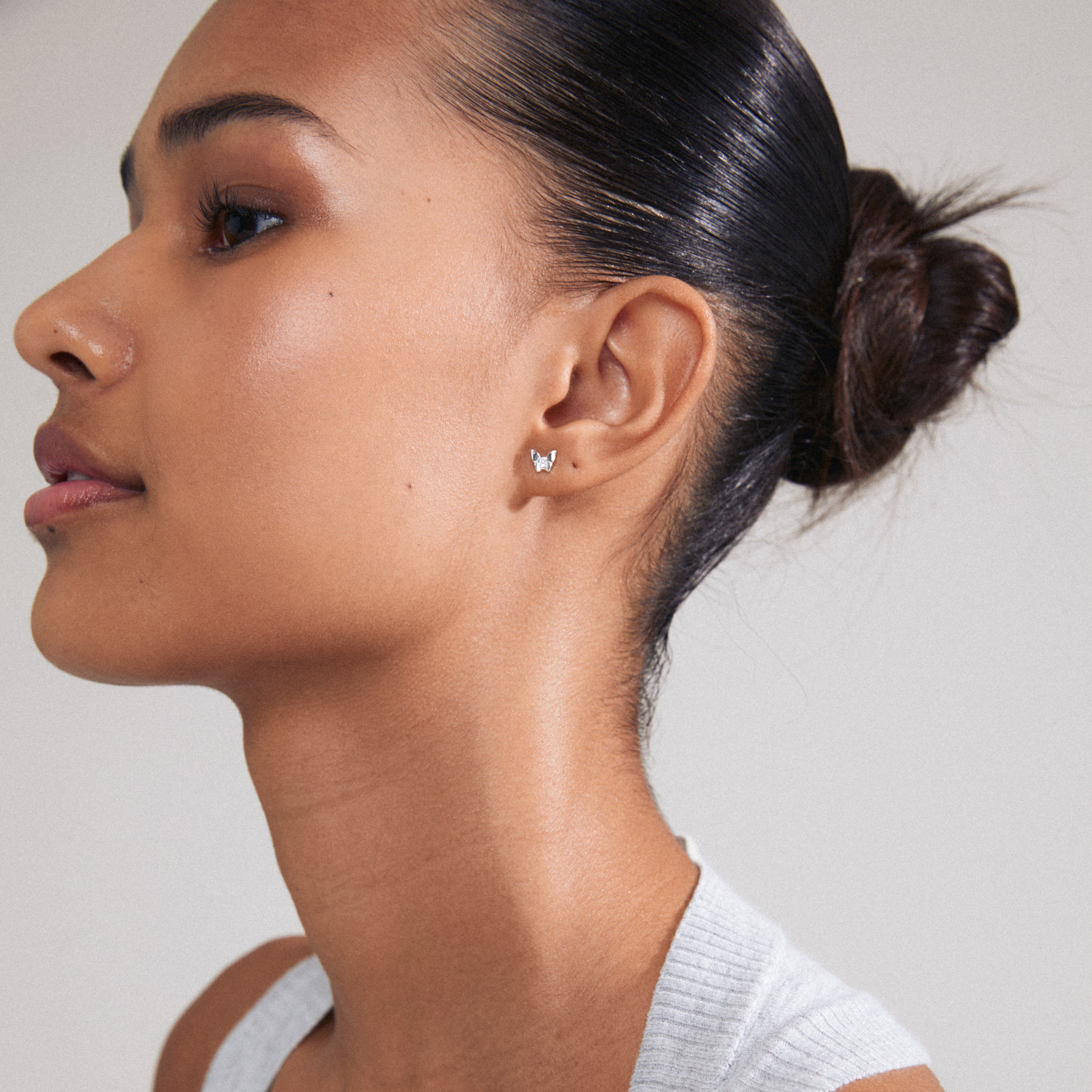 OLYMPIA single earring silver-plated featuring a delicate butterfly design with Preciosa crystals, showcased on a woman's ear with a bun hairstyle.