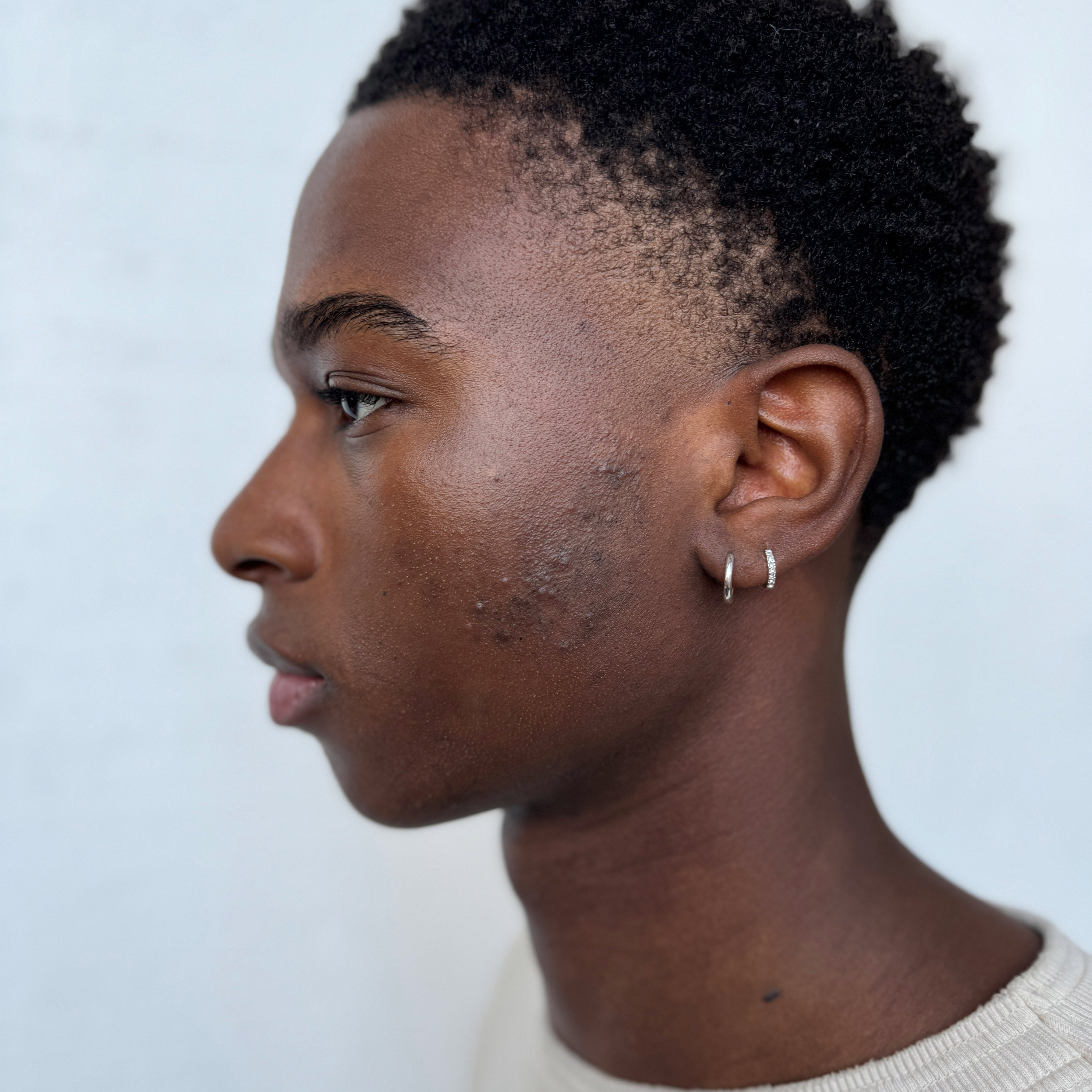 LAVRA single earring, silver-plated, shown in a man's ear. Timeless, shiny huggie hoop design with easy click clasp, perfect for a trendy, asymmetrical look.