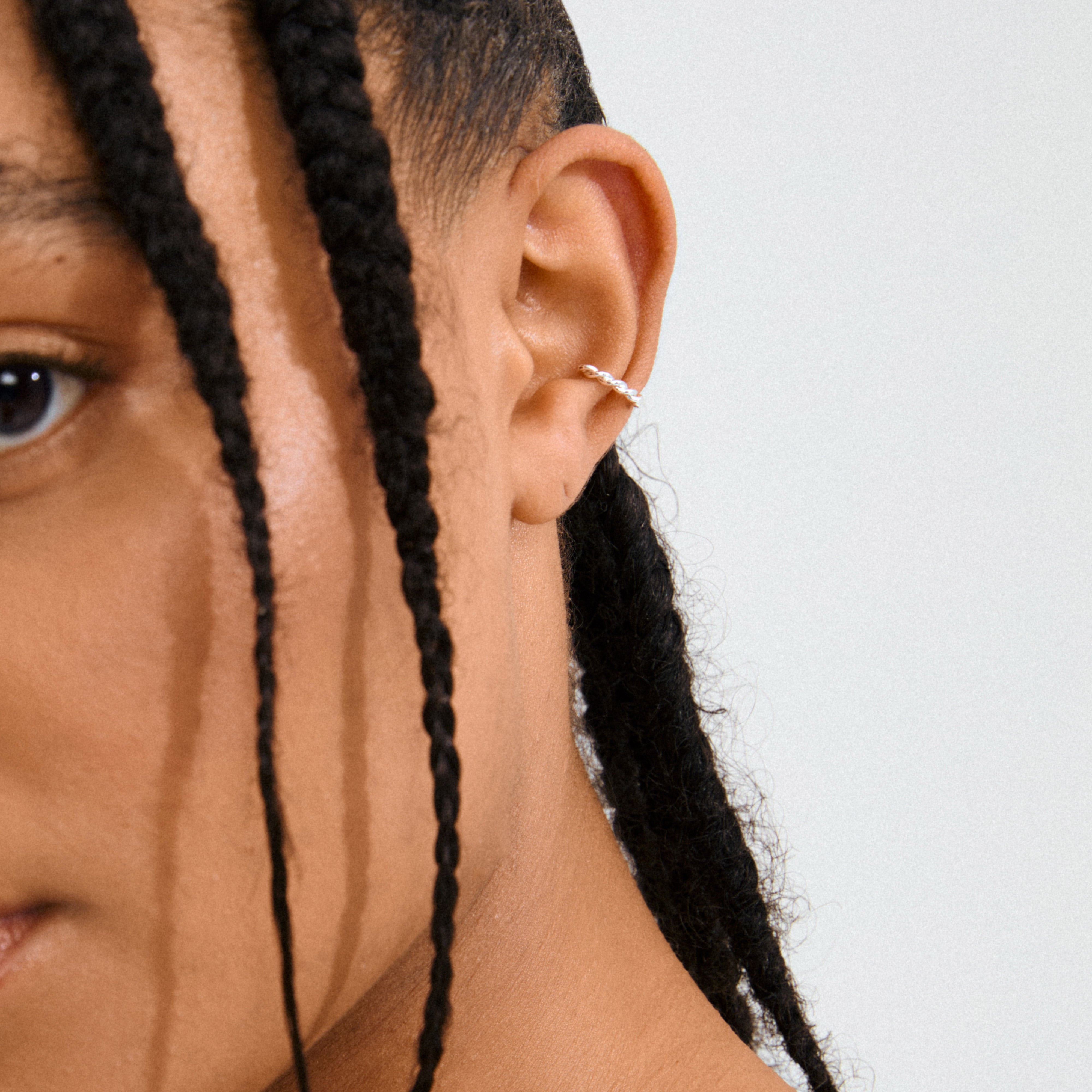 YAEL ear cuff silver-plated on a woman's ear, showcasing its twisted design. A stylish, piercing-free accessory for a unique, edgy look.