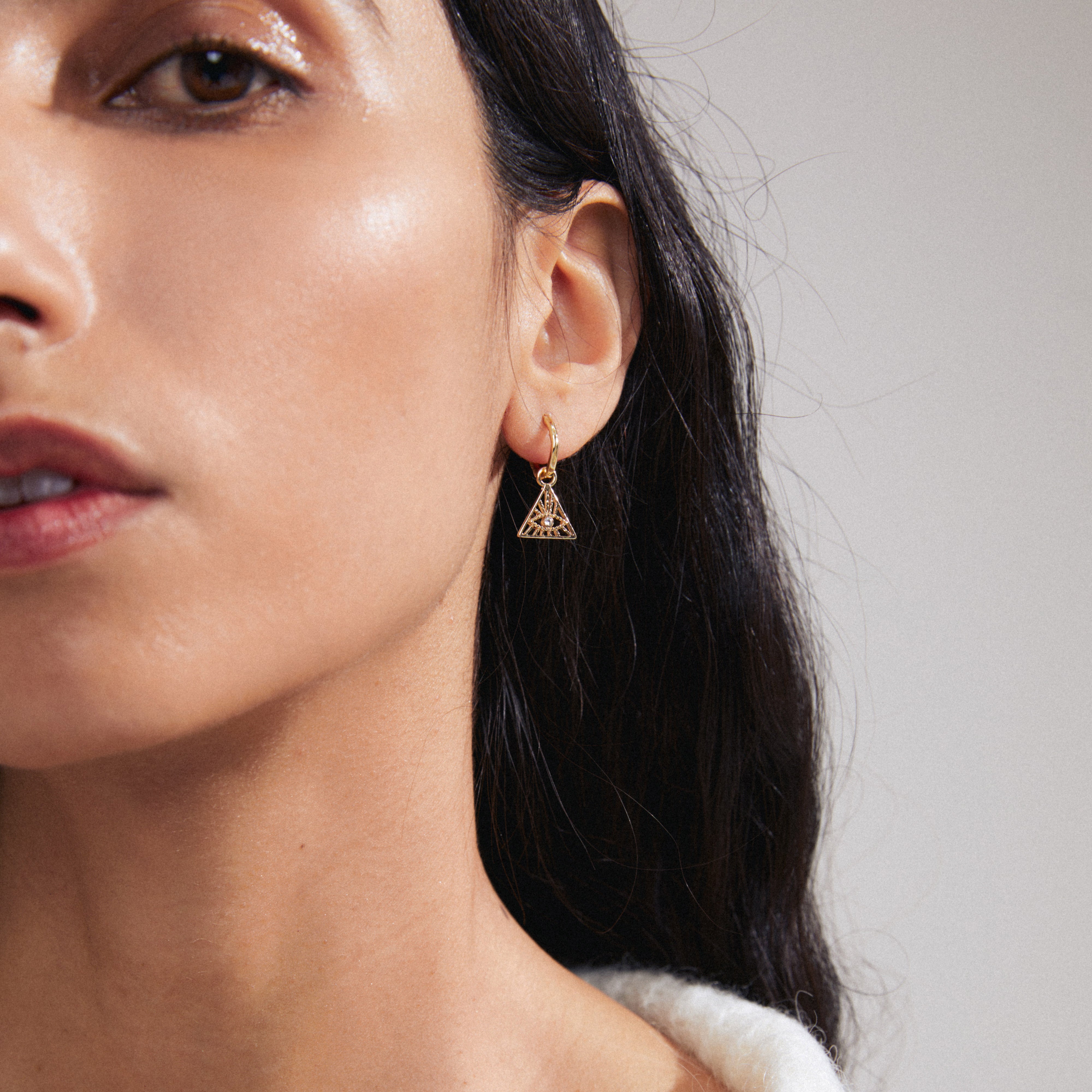 SIBYLLA single earring gold-plated, featuring a decorative triangle with Preciosa crystals, worn by a woman, showcasing Pilgrim's edgy, recycled, and personalized design.