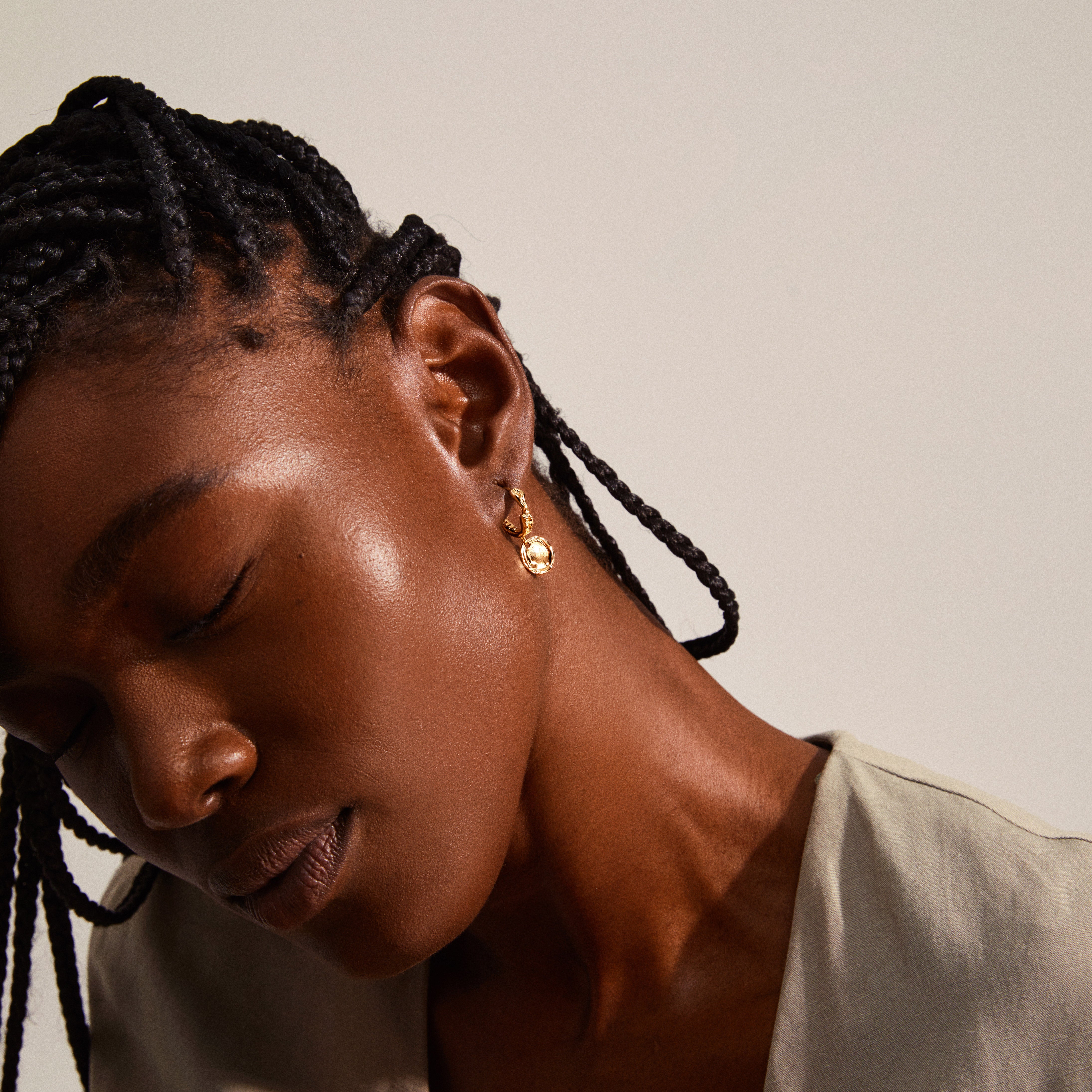 Close-up of a woman wearing Pilgrim's LEAF coin hoops gold-plated earrings, highlighting their unique organic shape and decorative coin pendants.