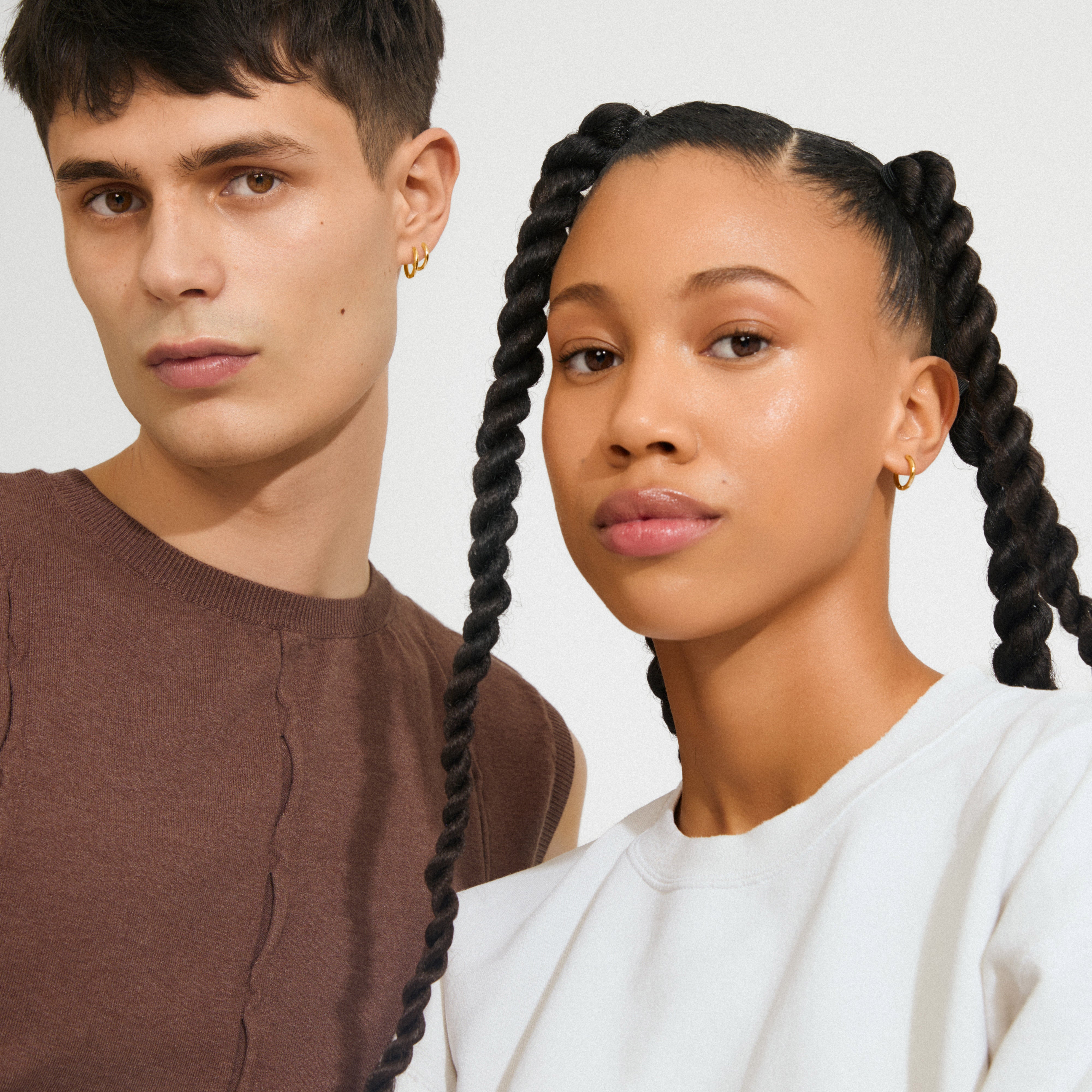 Two young adults wearing LEAF 2-in-1 set huggie hoops gold-plated, showcasing Pilgrim's classic, sustainable style with gold-plated mini hoops.