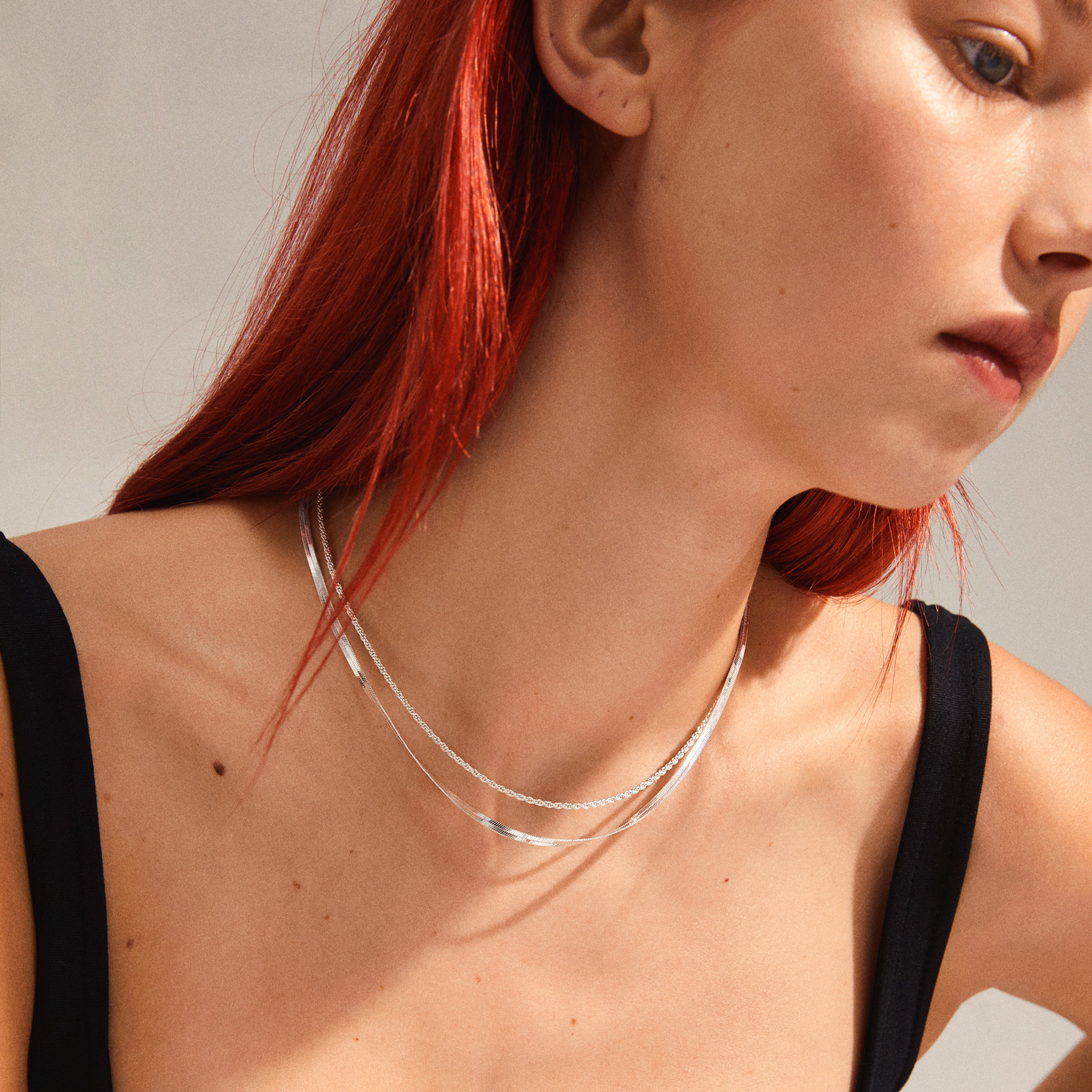 LEAF 2-in-1 set necklaces, silver-plated, featuring twisted rope and flat snake chains, elegantly worn by a red-haired woman, showcasing Pilgrim's recycled collection.