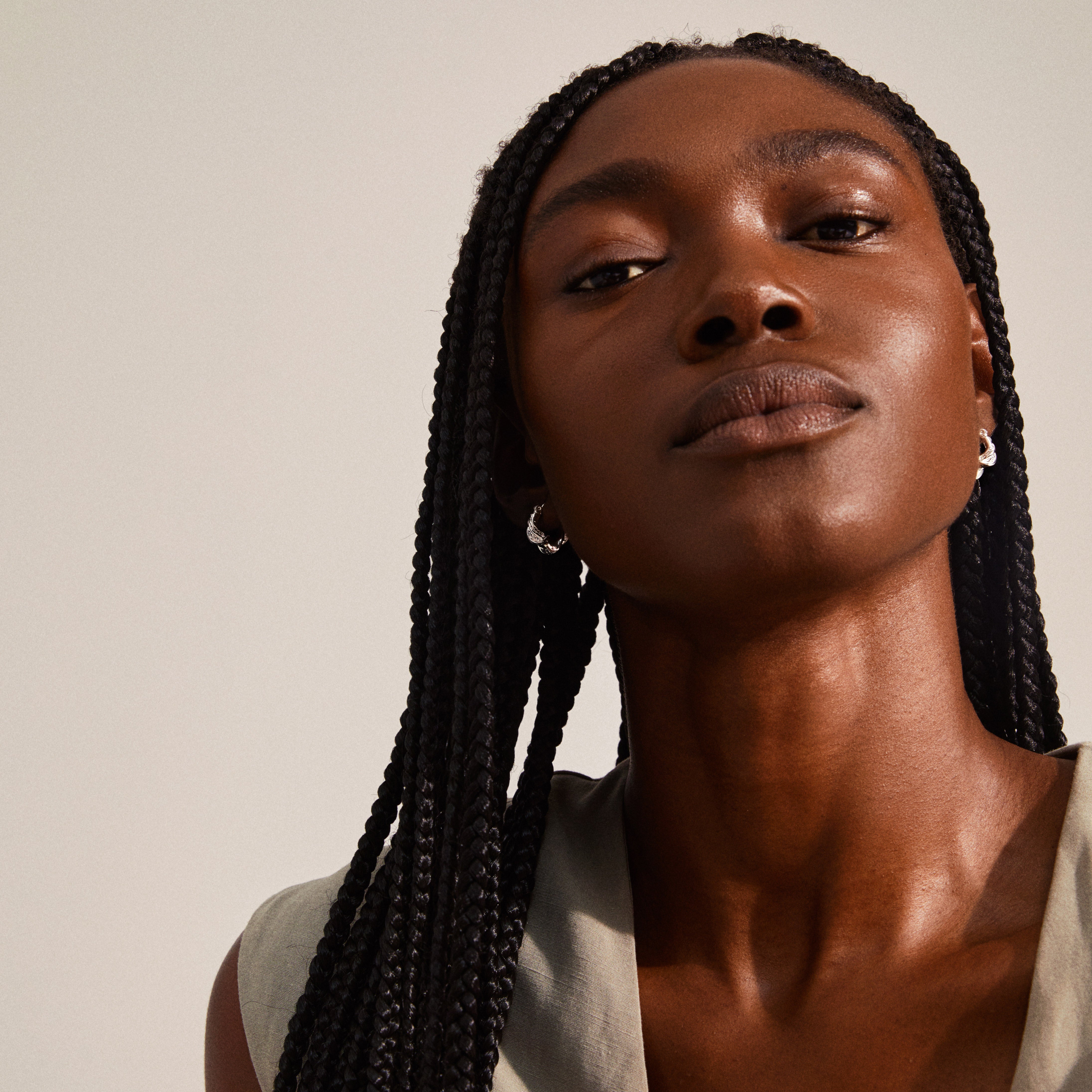LEAF twirl hoops silver-plated: A woman with long black braids wearing chunky, twisted silver-plated huggie earrings from Pilgrim's recycled LEAF collection.