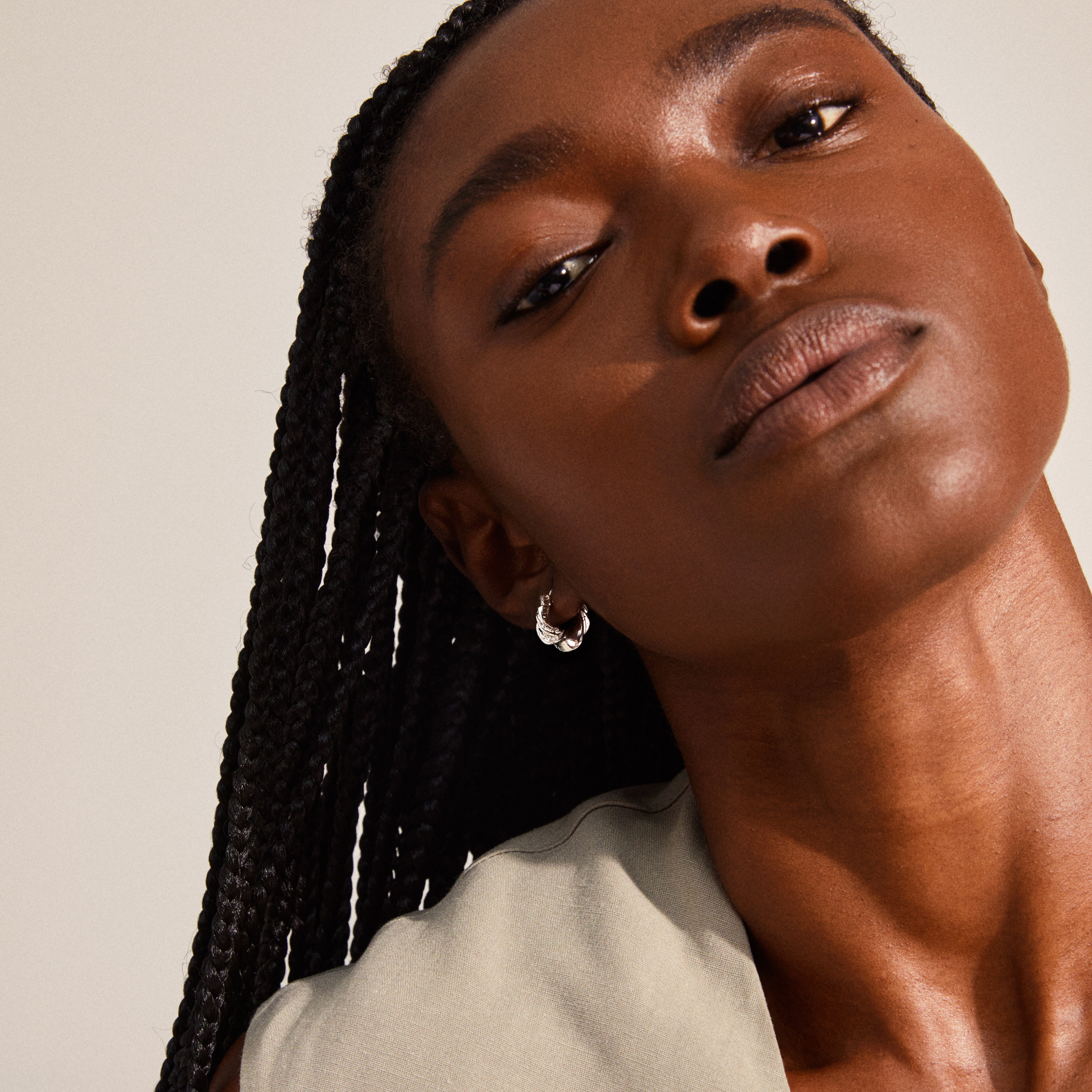 LEAF twirl hoops silver-plated adorn a woman's ear, showcasing chunky twisted design, part of Pilgrim's sustainable, recycled collection.