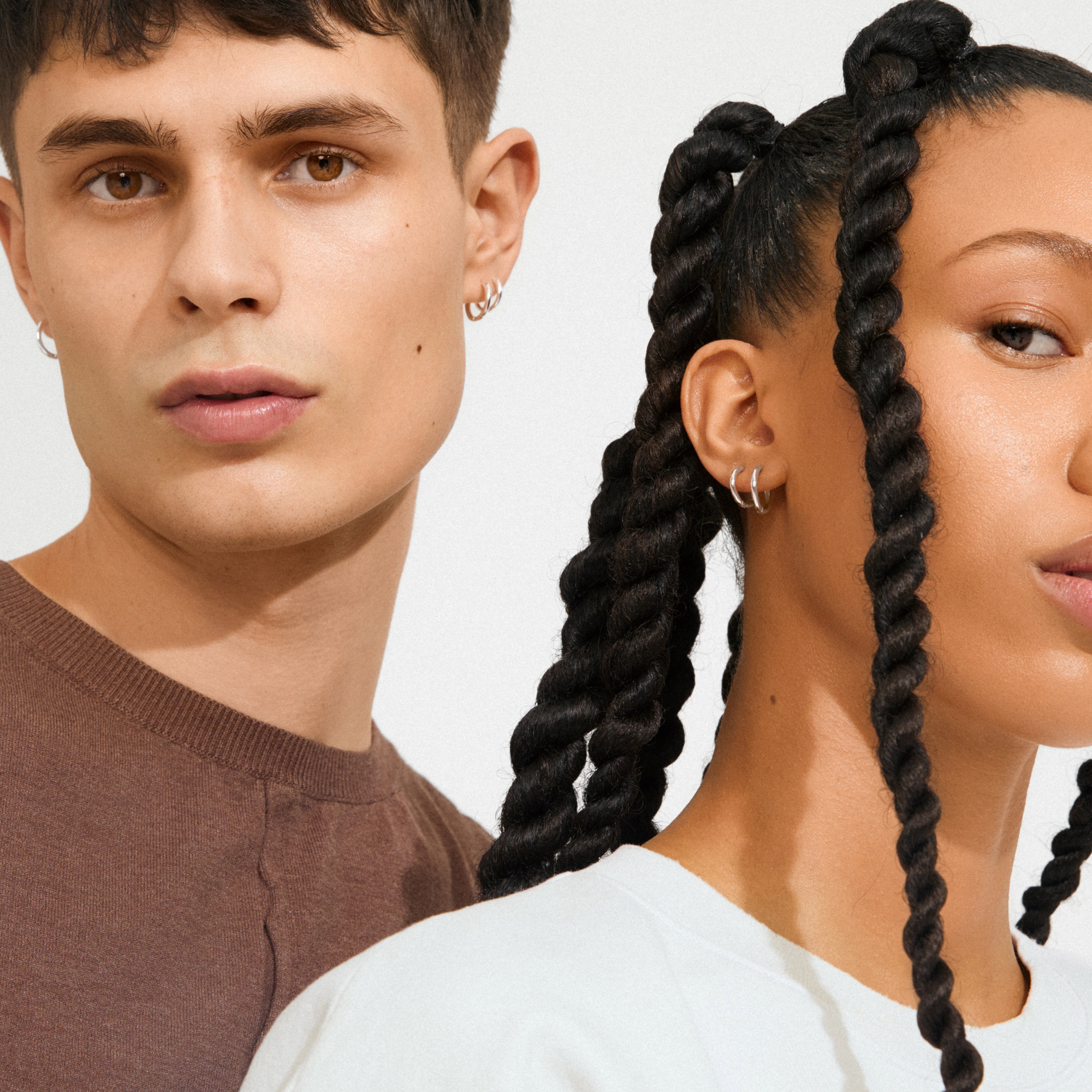 Two young adults showcasing Pilgrim's LEAF 2-in-1 set huggie hoops, silver-plated, adorning their ears with minimalist, stylish flair.