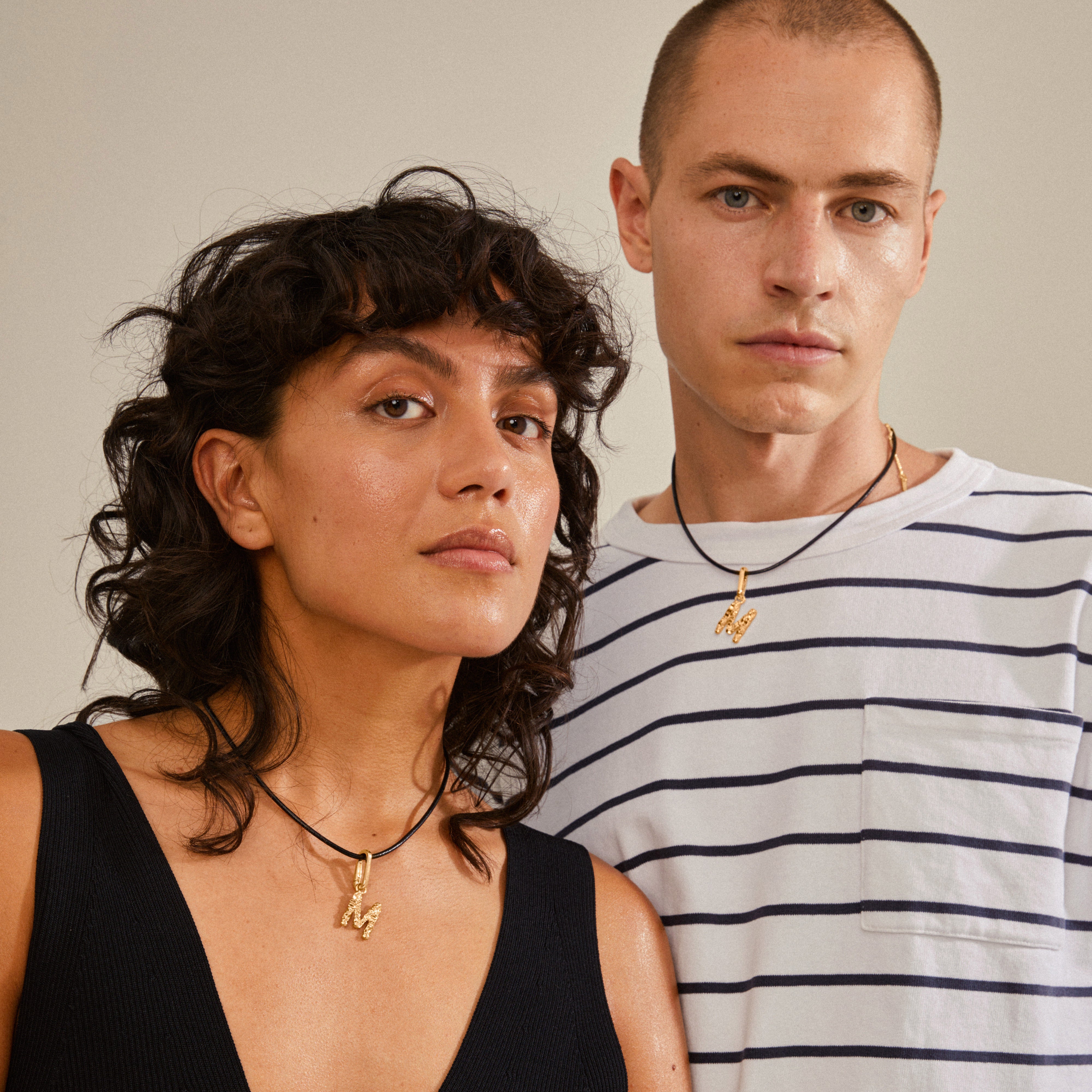 Gold-plated CHARM pendant M worn by a woman, showcasing a stylish and personalized look with a focus on sustainable, recycled materials.