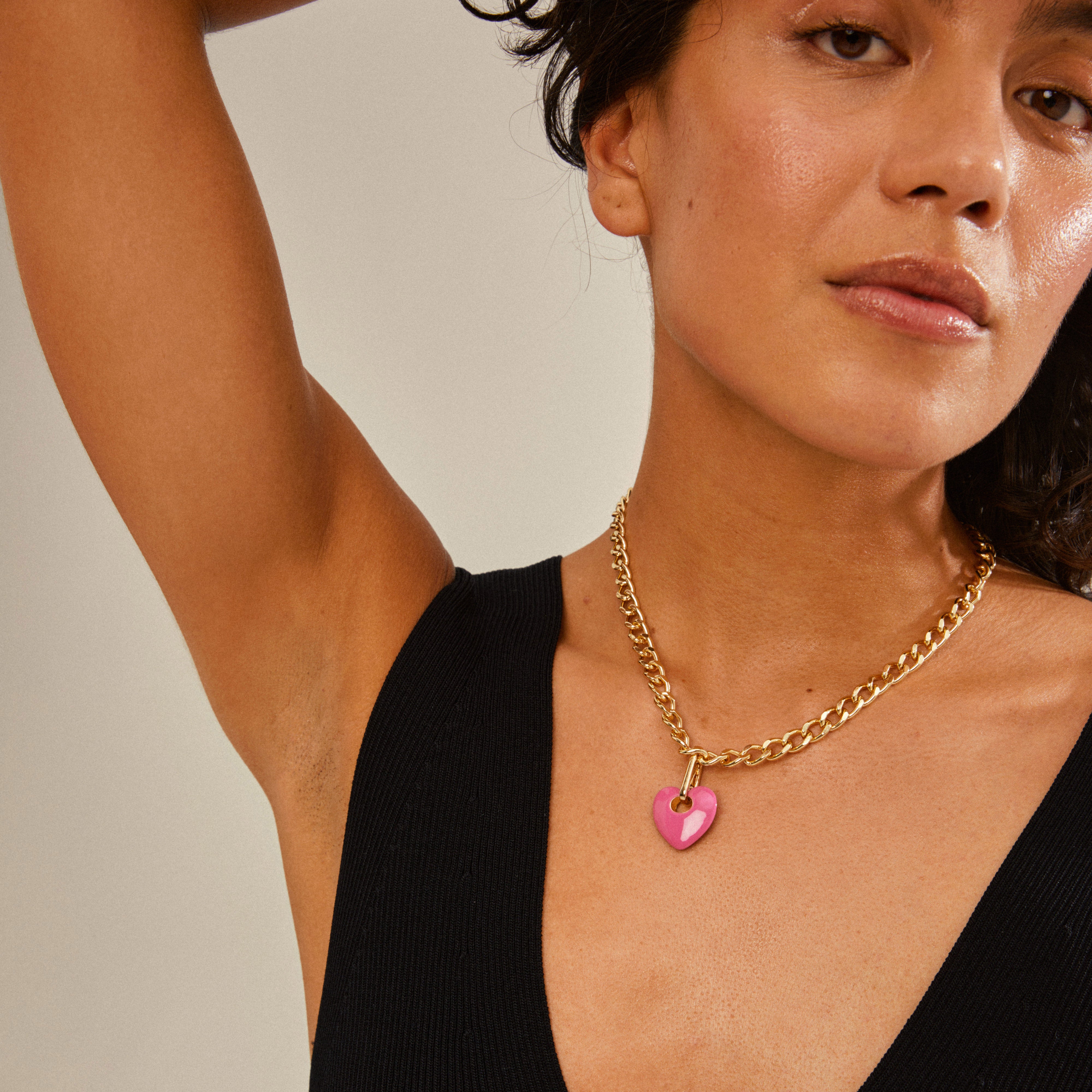 Woman wearing Pilgrim's CHARM heart pendant, pink/gold-plated, showcasing a stylish and personalized fashion accessory with a close-up of the necklace.