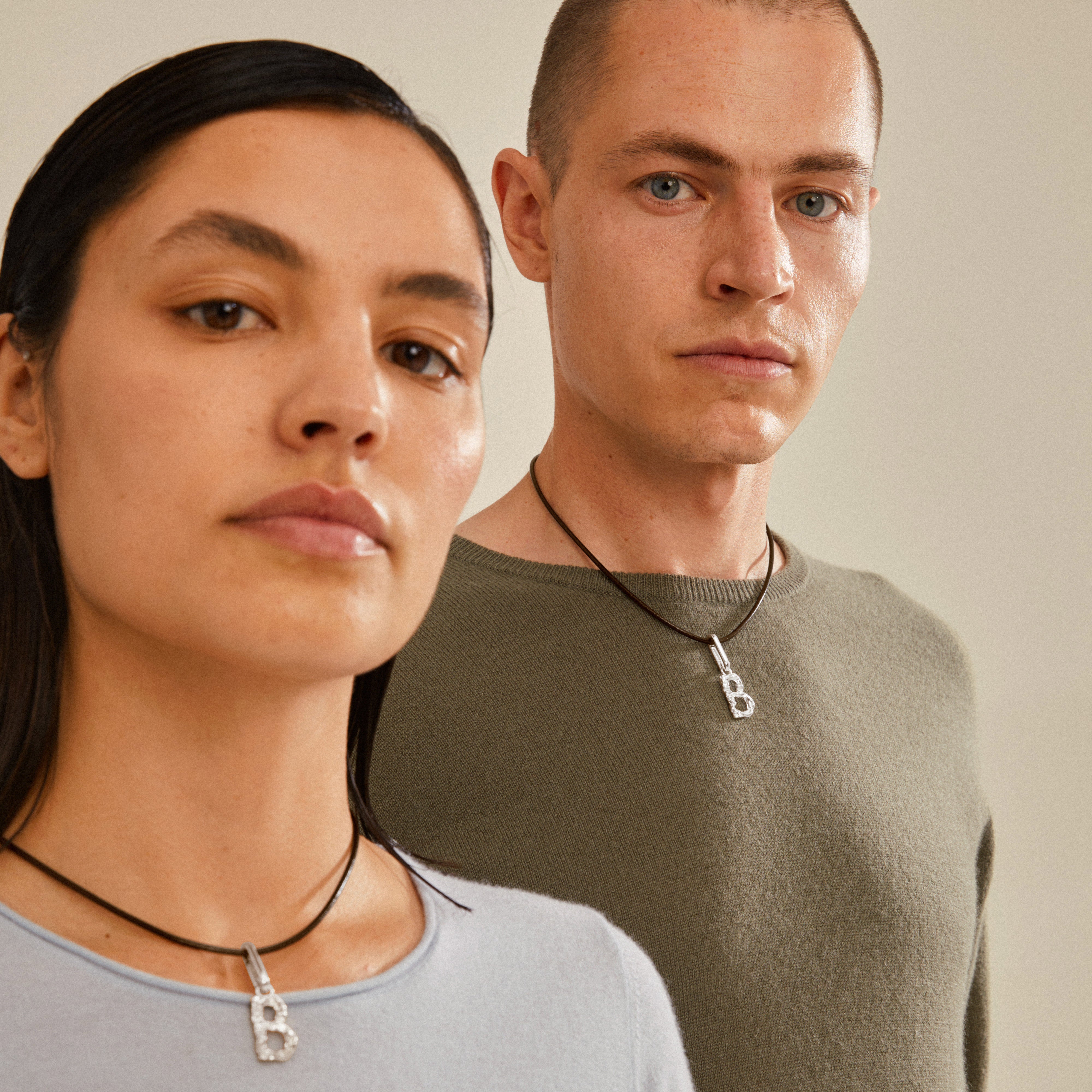 CHARM pendant B, silver-plated, showcased by a man and woman, offering a unique and personalized style with rustic elegance, perfect for trendsetters.