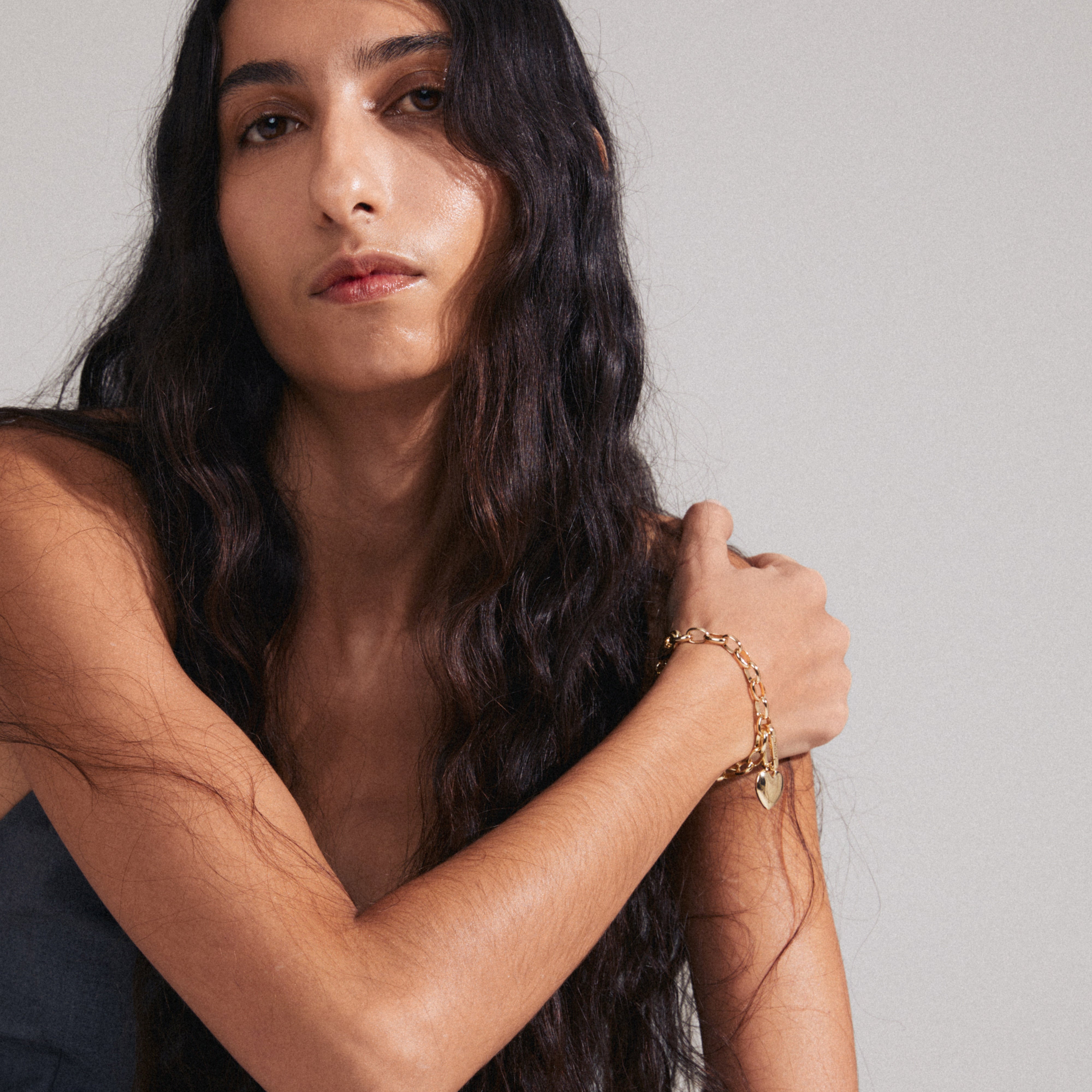 A woman models Pilgrim's gold-plated CHARM heart pendant, showcasing its elegant design and personal style potential.