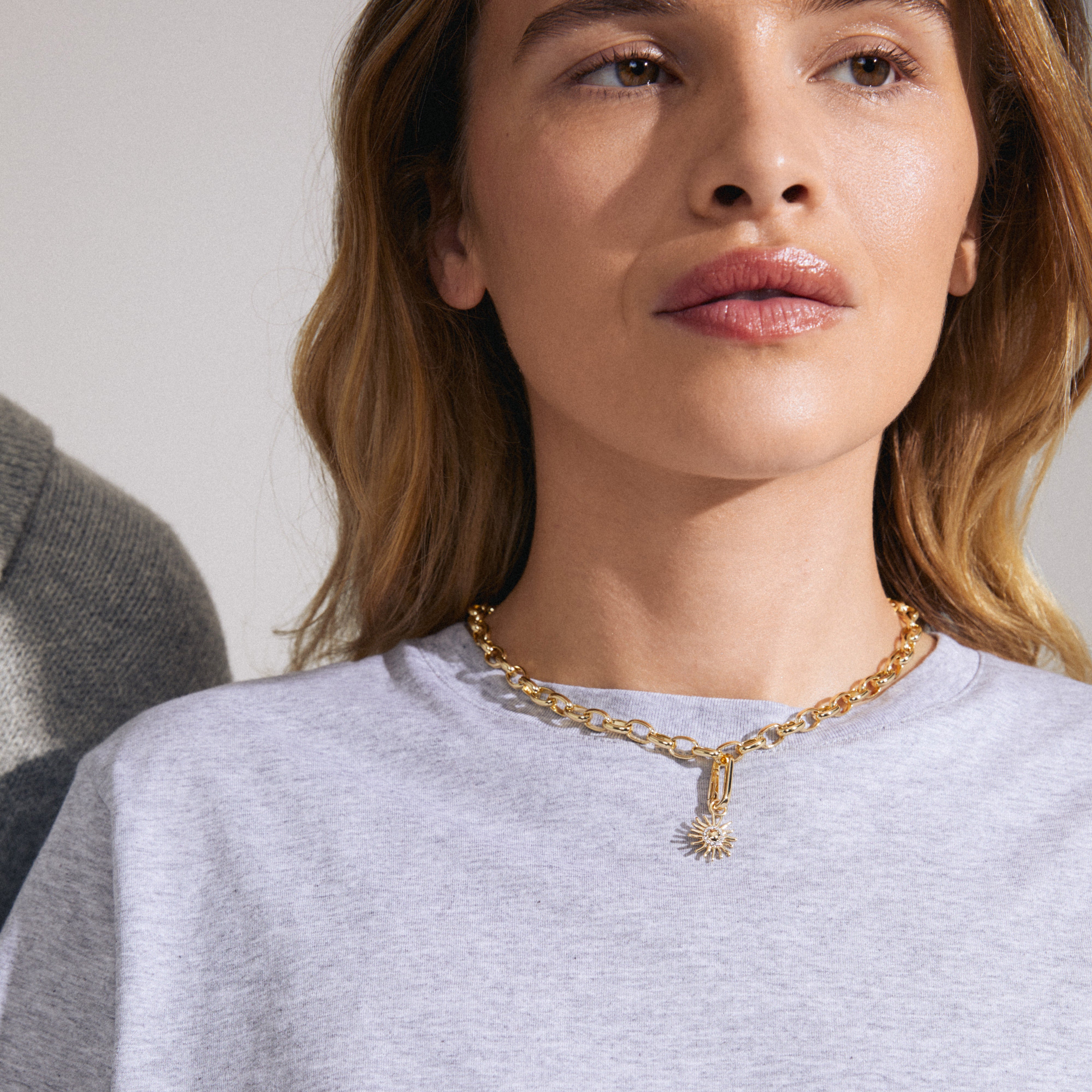 Woman wearing the Pilgrim CHARM sun pendant, gold-plated, adorned with Preciosa crystals, highlighting its unique design and personalized styling potential.