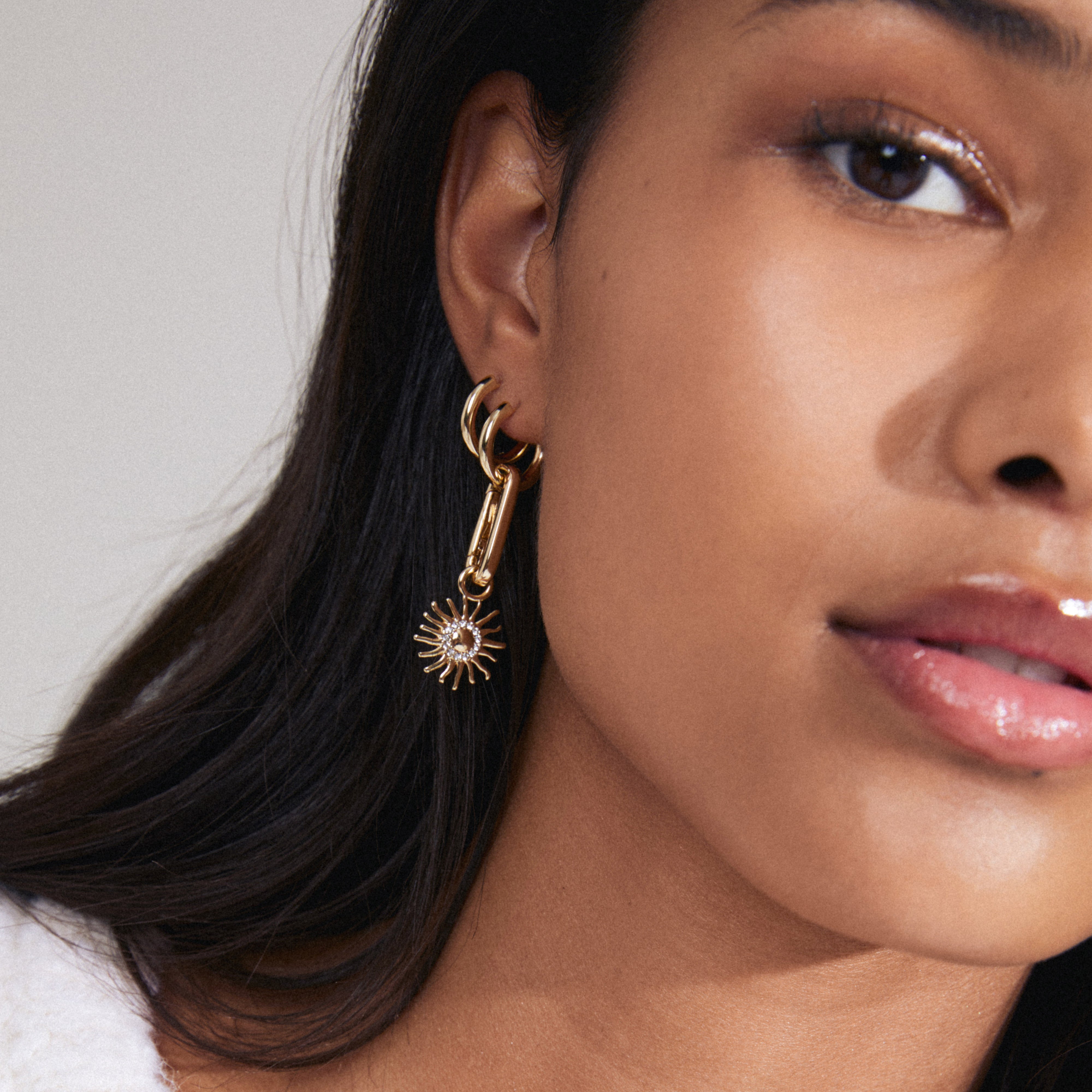 Close-up of a woman wearing Pilgrim's CHARM sun pendant, gold-plated with Preciosa crystals, highlighting its unique design and elegant appeal.