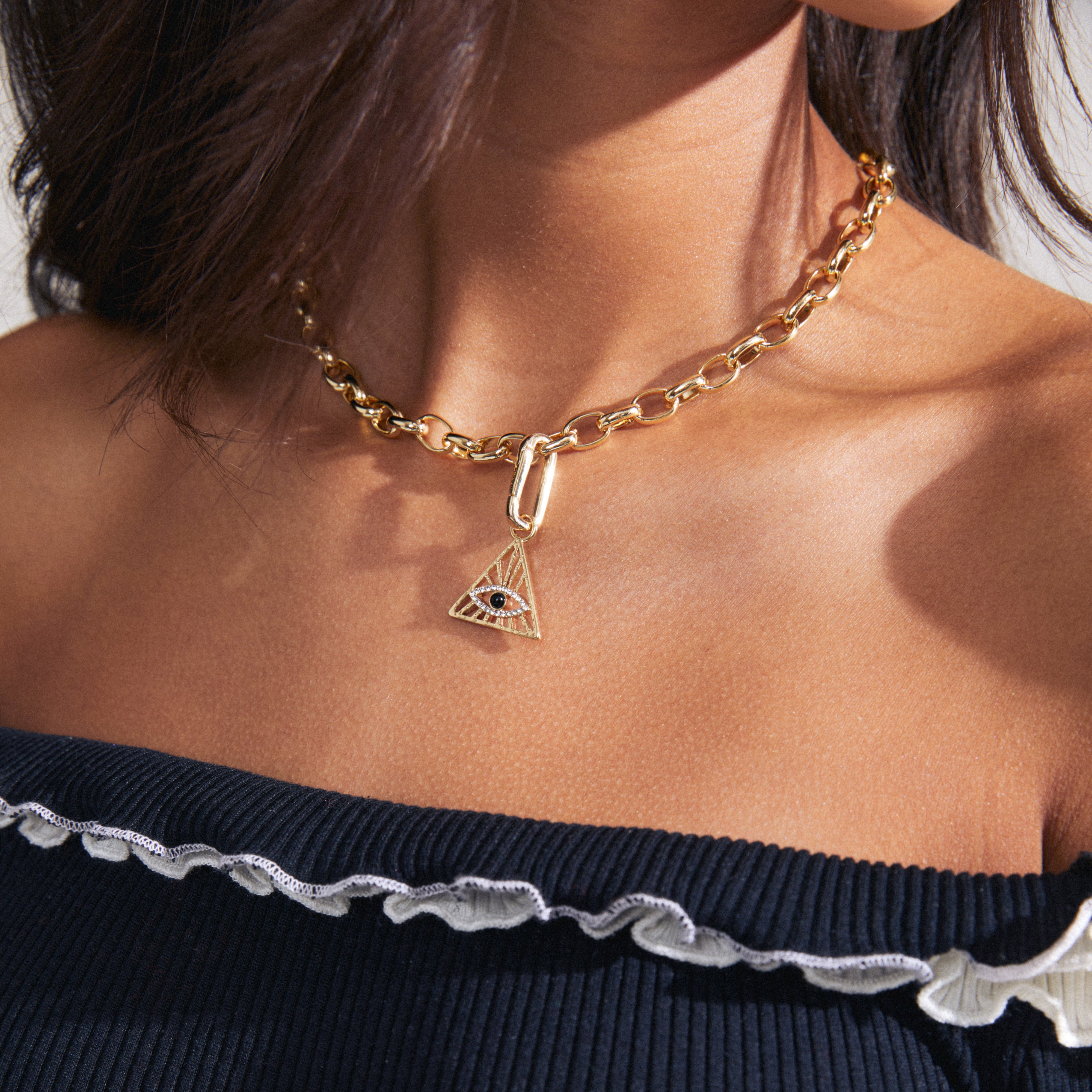 Woman wearing Pilgrim's CHARM triangle pendant, gold-plated, featuring an all-seeing eye design, adding a unique touch to her style.