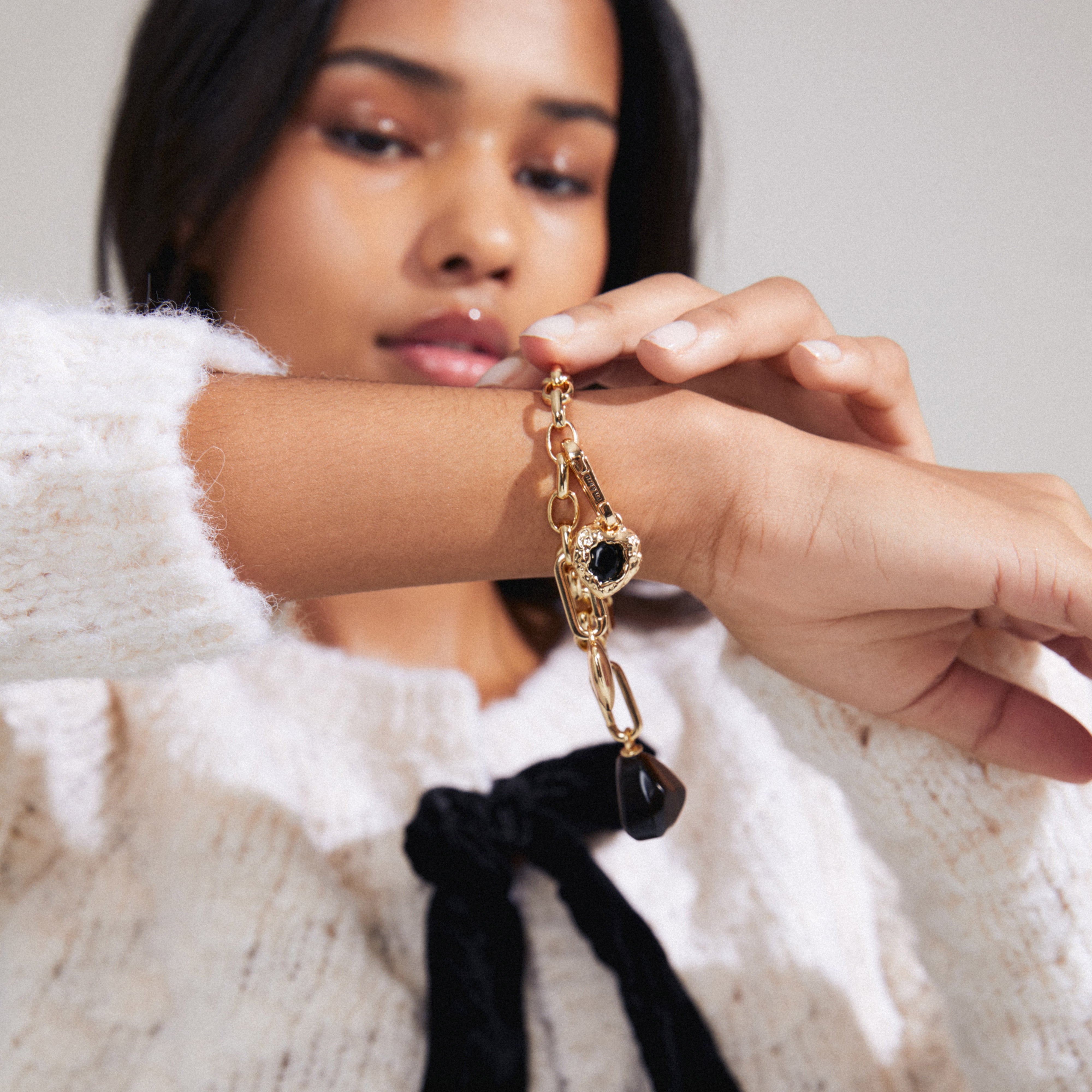 A woman elegantly models the CHARM black agate pendant, gold-plated, highlighting its distinct, personal style appeal for trendy accessorizing.