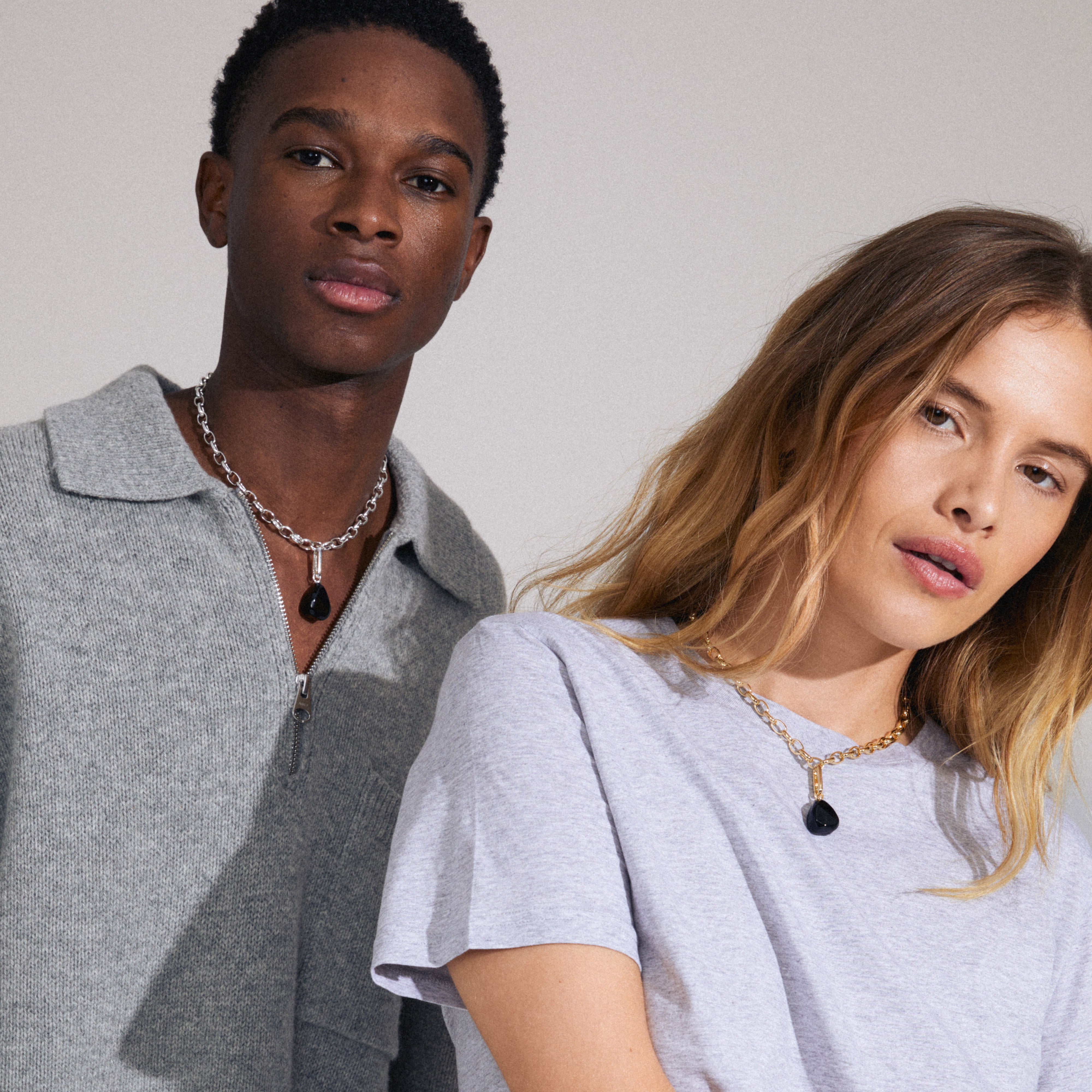 Man and woman showcasing Pilgrim's CHARM black agate pendant, gold-plated, worn as a fashion accessory with a necklace, highlighting its stylish and personalizable design.