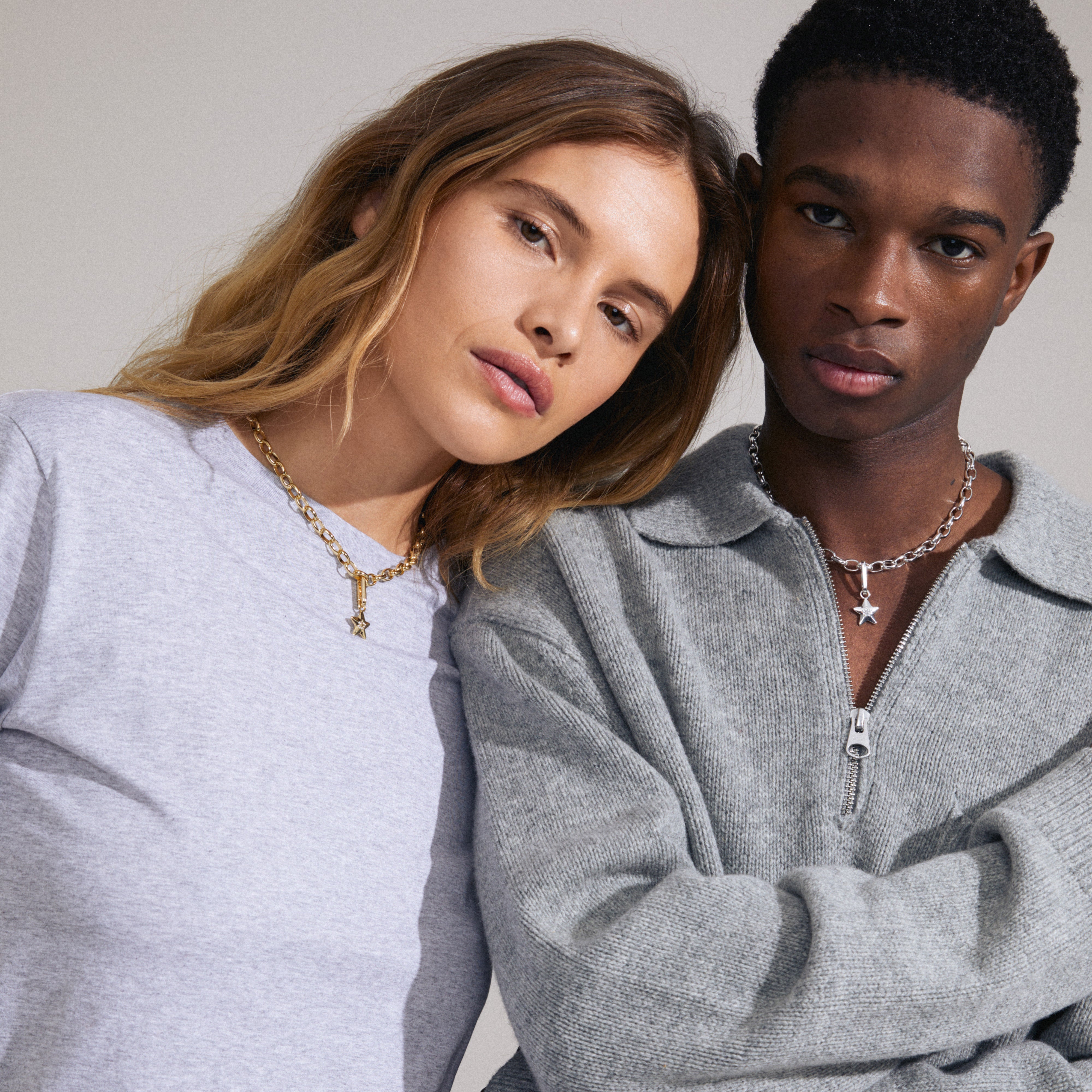 Man and woman showcasing Pilgrim's CHARM star pendant, silver-plated, adorned with Preciosa crystals, highlighting its versatile styling on necklaces or hoops.