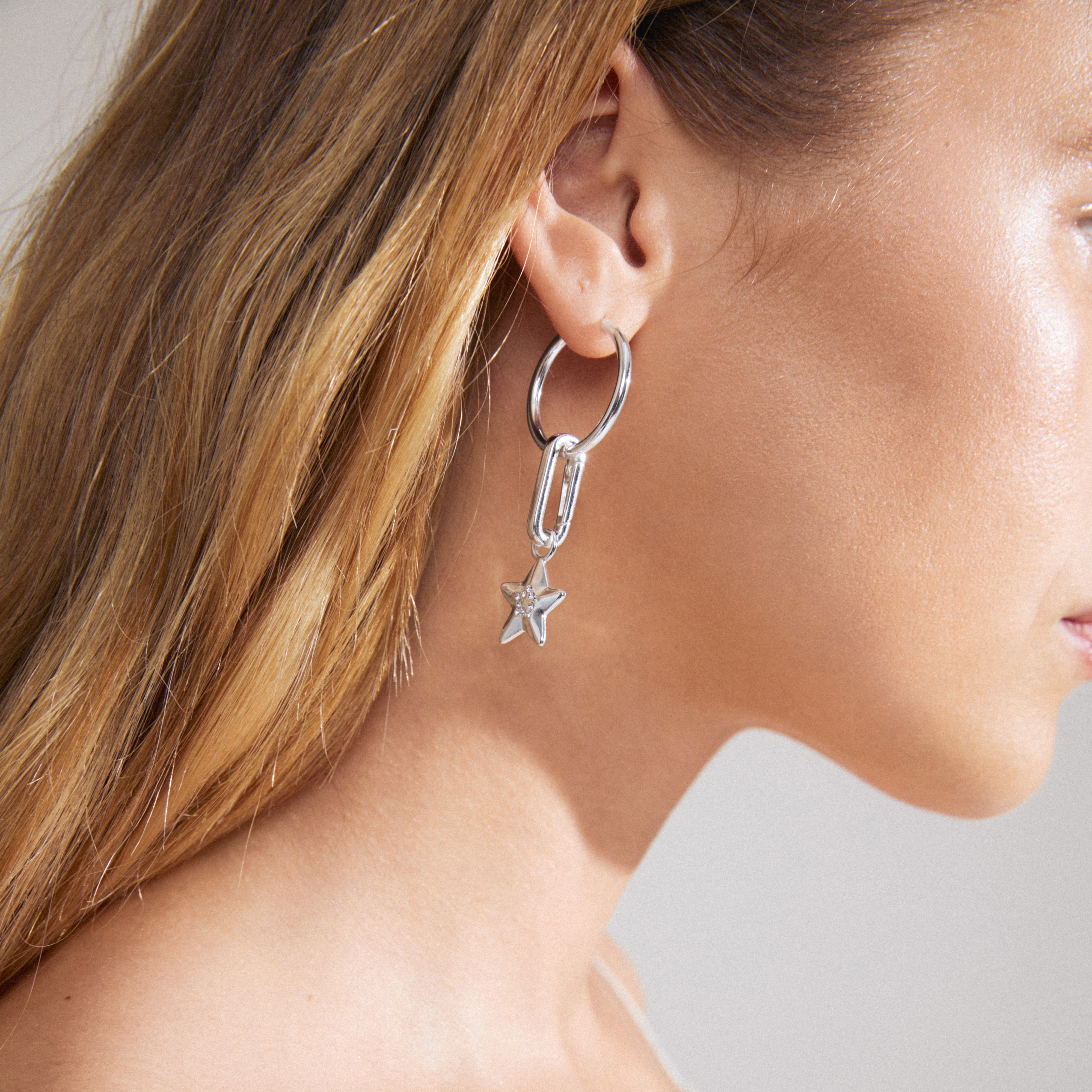 Woman wearing Pilgrim's CHARM star pendant, silver-plated with Preciosa crystals, illustrating a unique style statement through trendy and responsibly crafted jewelry.