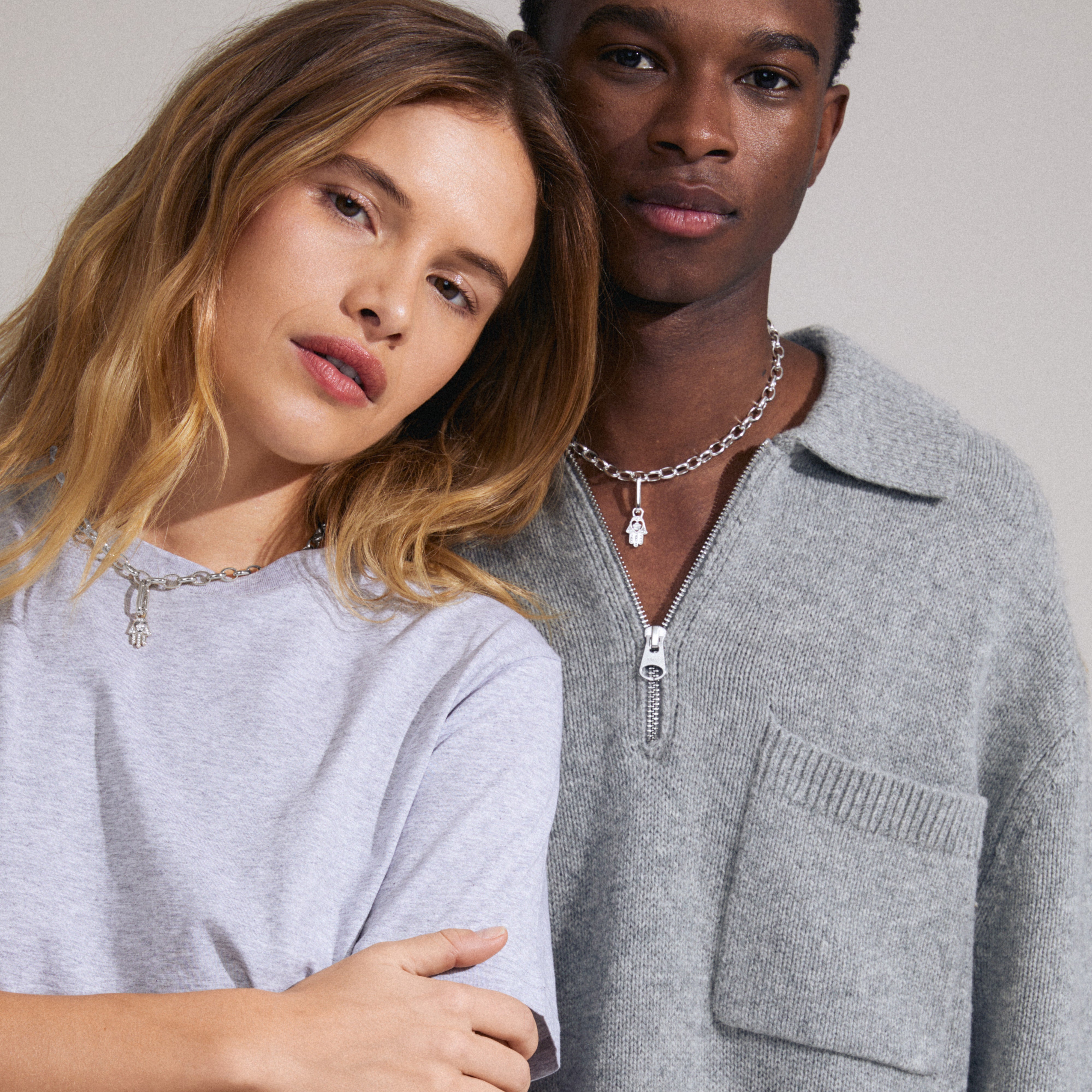 A man and woman pose, highlighting the CHARM Hamsa pendant, silver-plated with Preciosa crystals, emphasizing Pilgrim's trendy, personalized jewelry style.