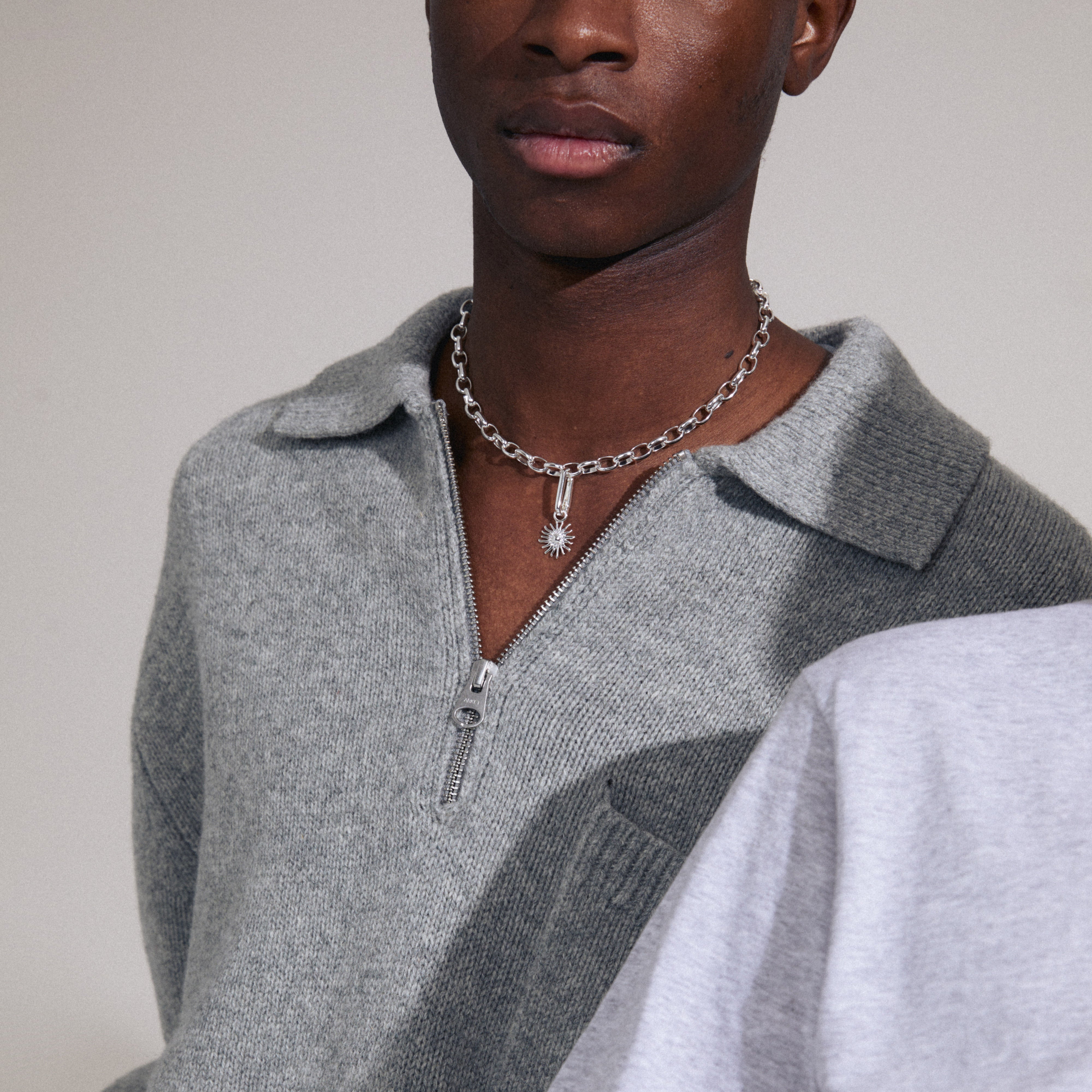 Man wearing a necklace featuring Pilgrim's CHARM sun pendant, silver-plated with Preciosa crystals, showcasing a stylish and personalized accessory option.