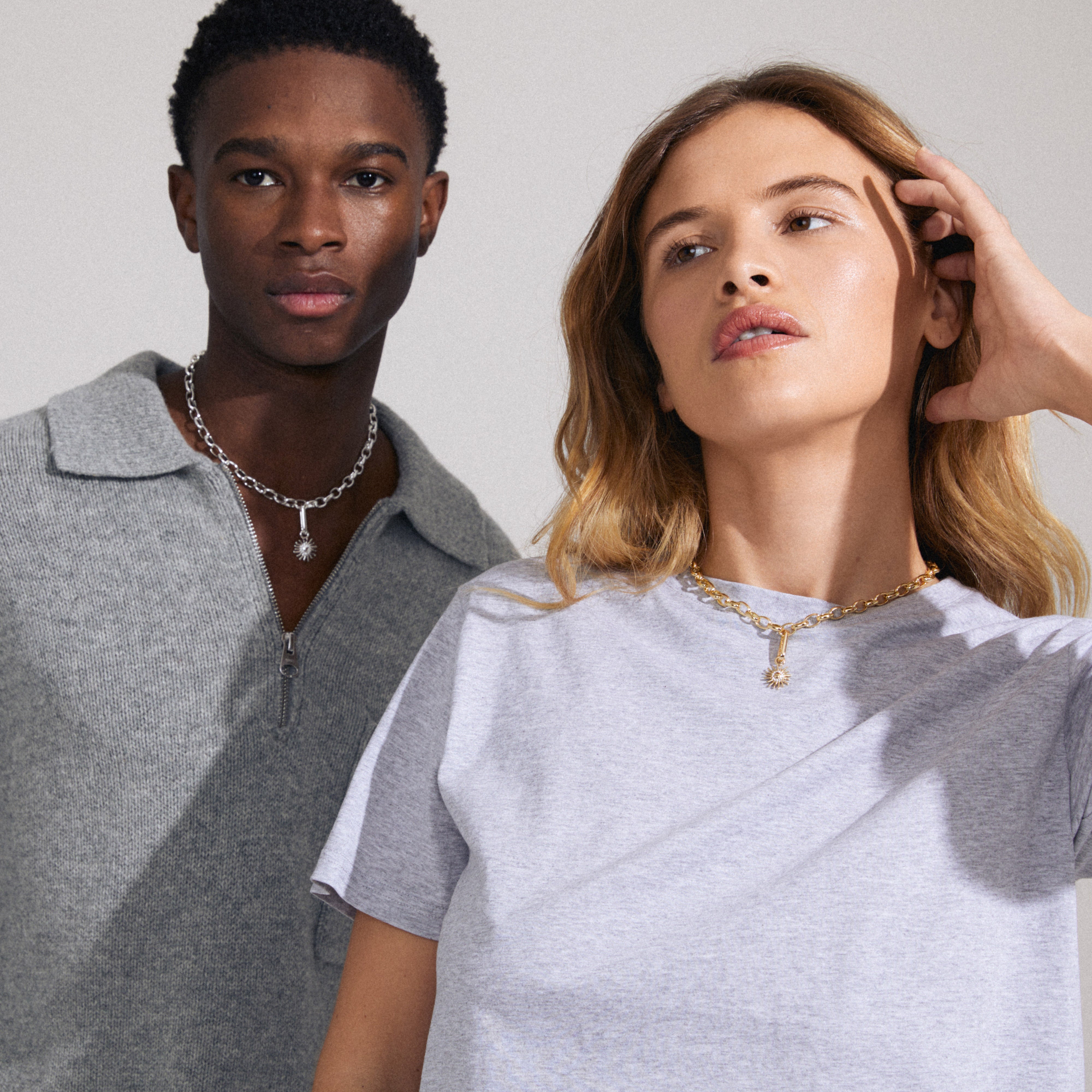 Man and woman showcasing Pilgrim's CHARM sun pendant, silver-plated, adorned with Preciosa crystals, highlighting its personalized styling potential.
