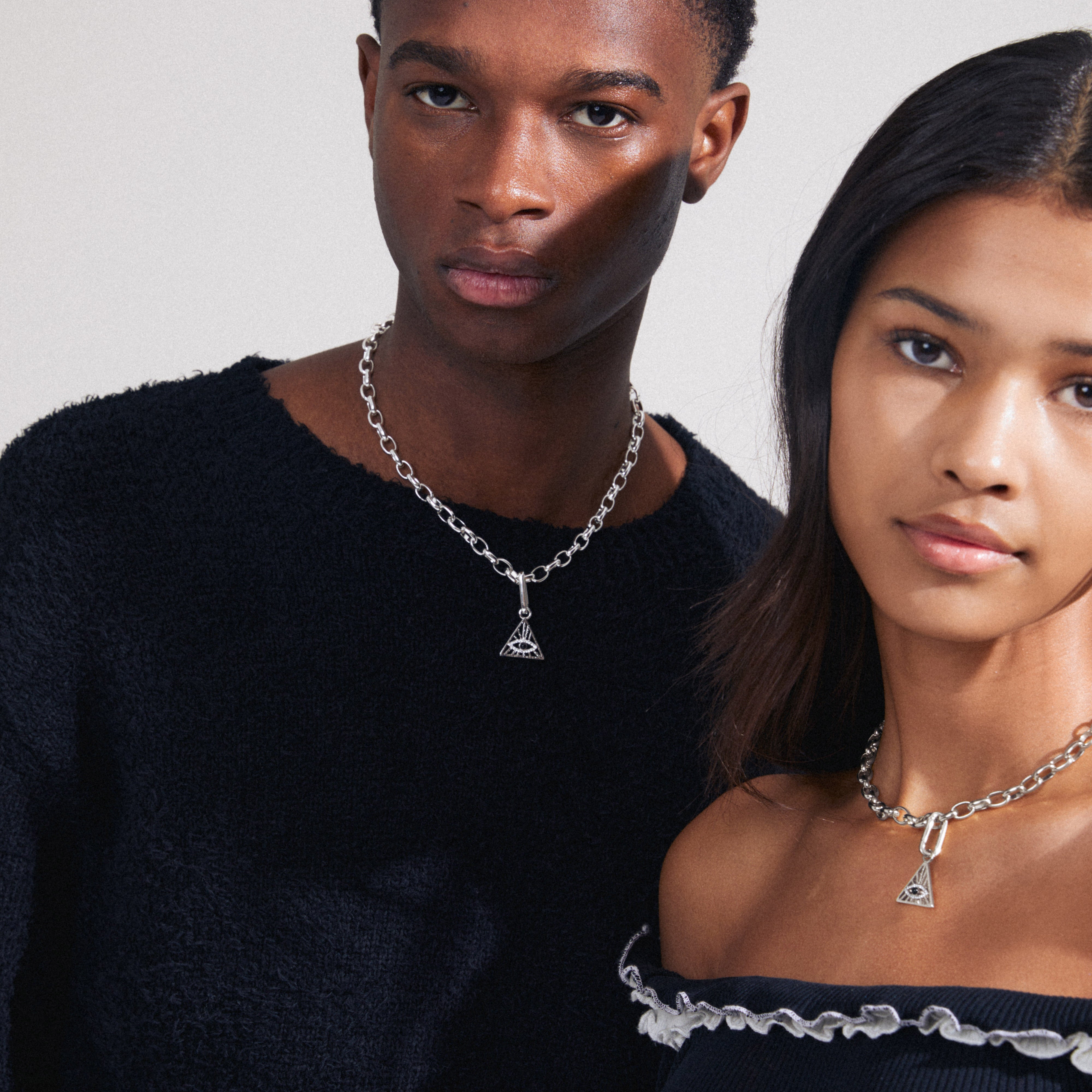 A man and woman wearing Pilgrim's CHARM triangle pendant, silver-plated, showcasing its unique design and symbolic all-seeing eye detail.