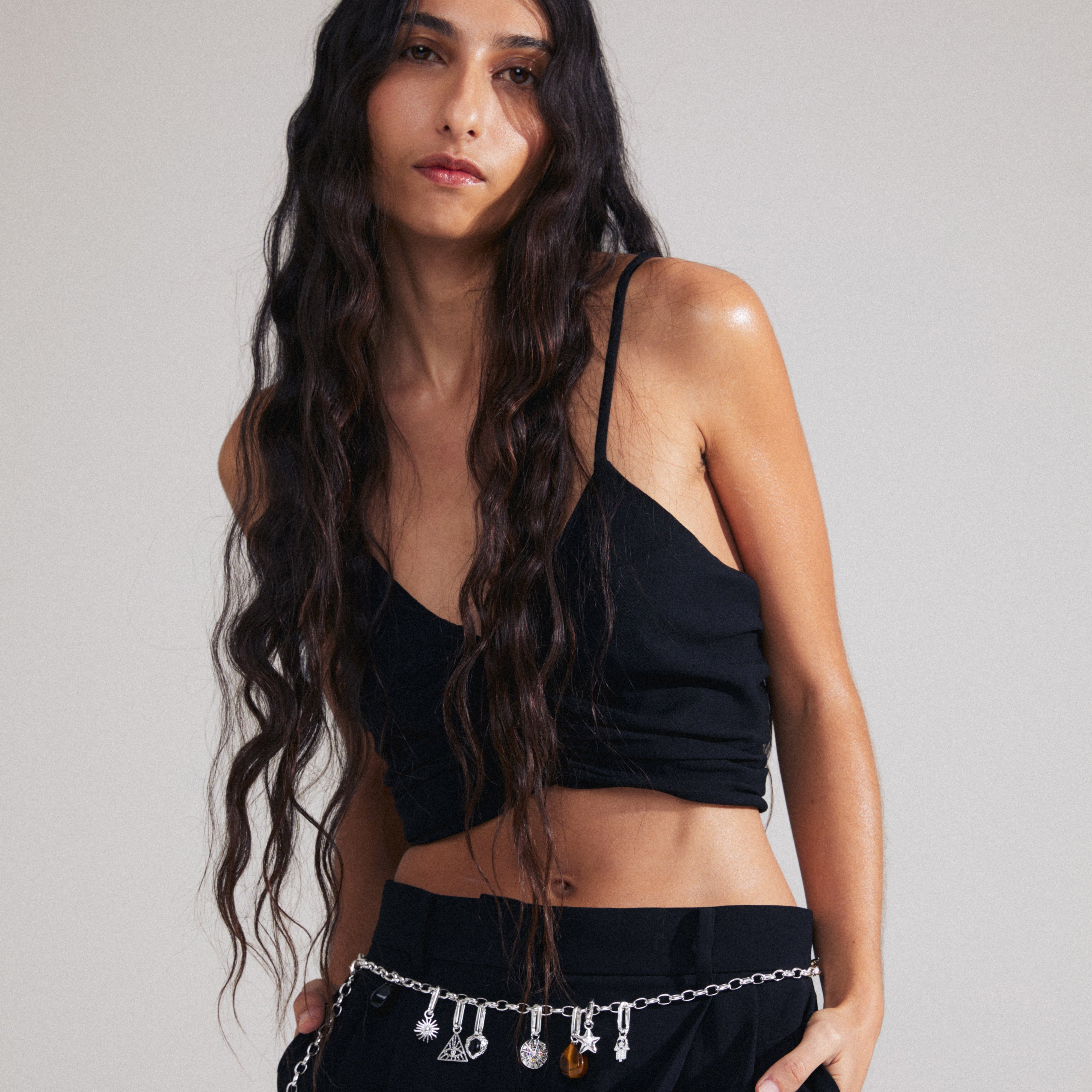 Woman wearing a black top and sunglasses, showcasing Pilgrim's CHARM triangle pendant, silver-plated, with an all-seeing eye, highlighting personalized and unique styling.